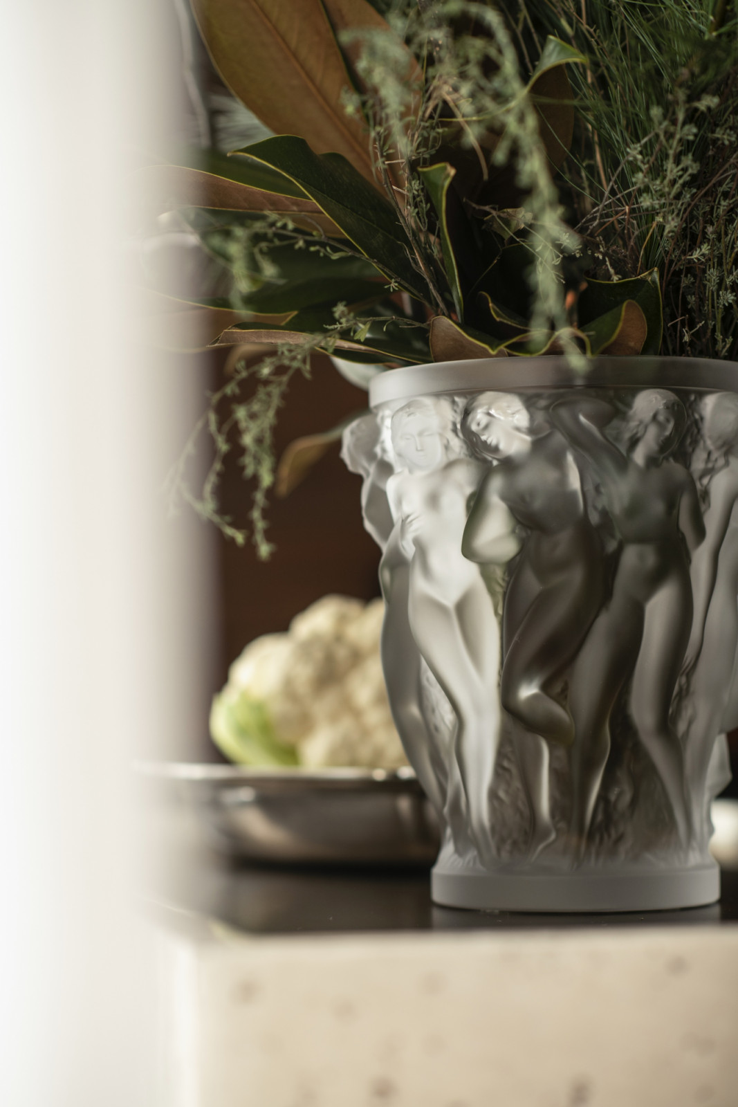 A Lalique Bacchantes vase used as a table centrepiece at Monti, filled with foraged greenery alongside a cauliflower set out for service (Photo: Giulio Ghirardi)