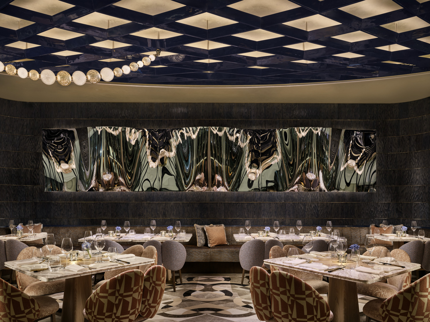 A banquette dining area at Akira Back Hong Kong set against a large-scale abstract wall installation in dark resin, beneath the navy and gold geometric ceiling (Photo: Owen Raggett)
