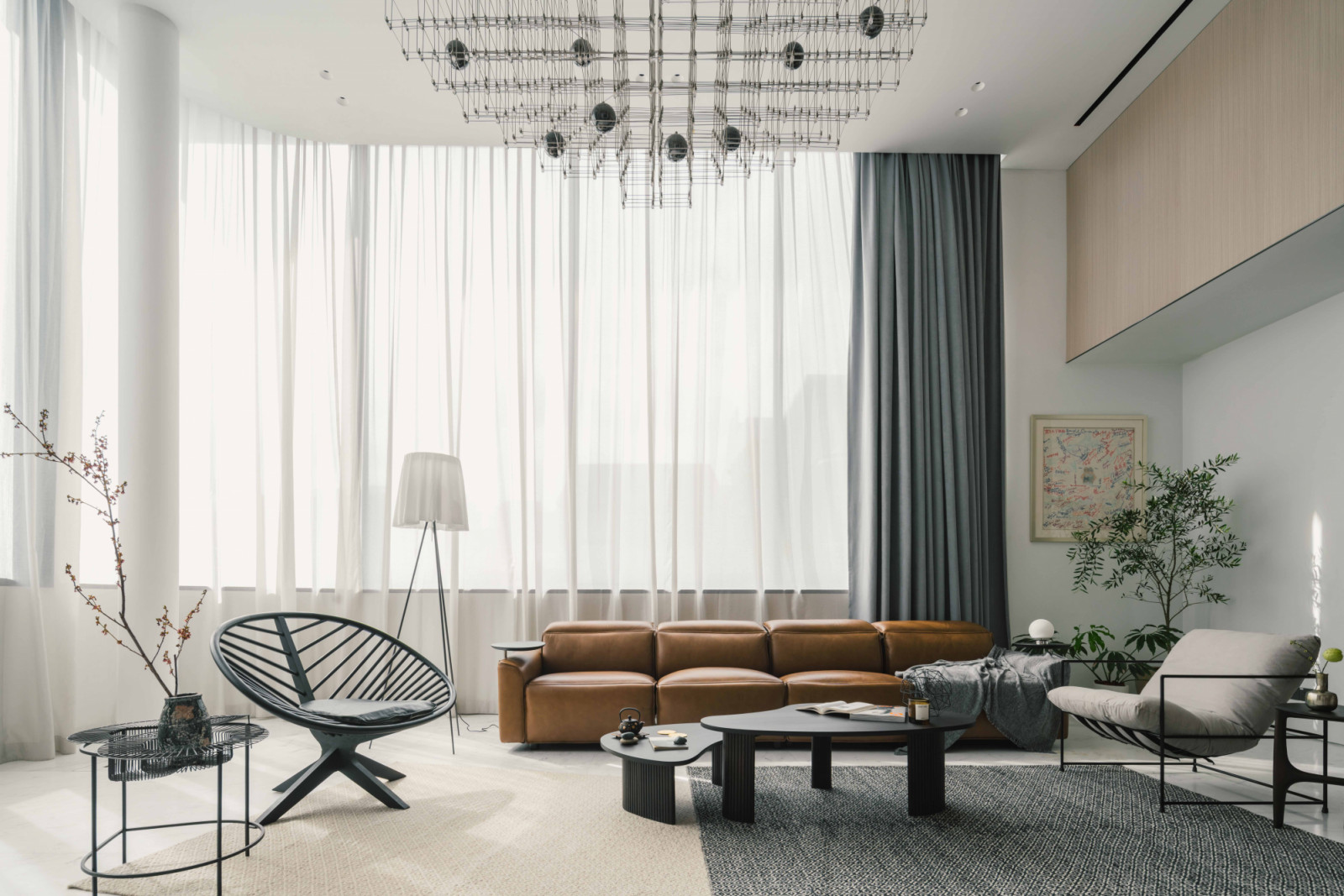 The double-volume living area is furnished with the King Cloud Recliner from King Living, a Flos floor lamp, and indoor plants from Arbour that were carefully selected for their aesthetic appeal and air-purifying qualities