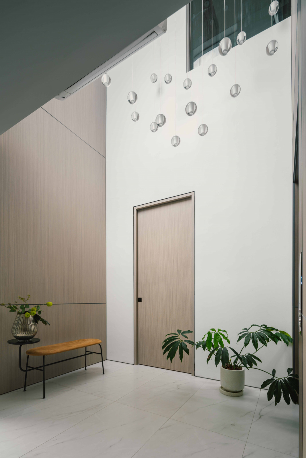 To access the living room, visitors traverse a narrow yet lofty semi-outdoor foyer located between the two wings of the house