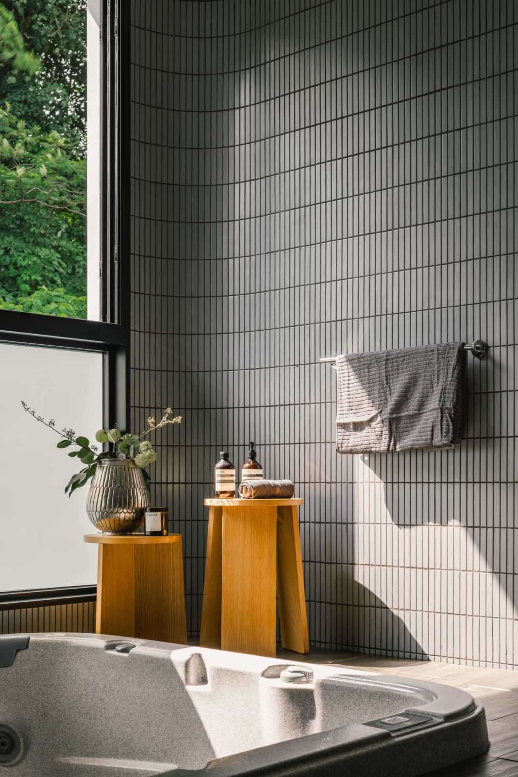 Sunlight streams into the bathroom, where green and grey elements of the pebble wash tiles were chosen for their resemblance to the forest floor