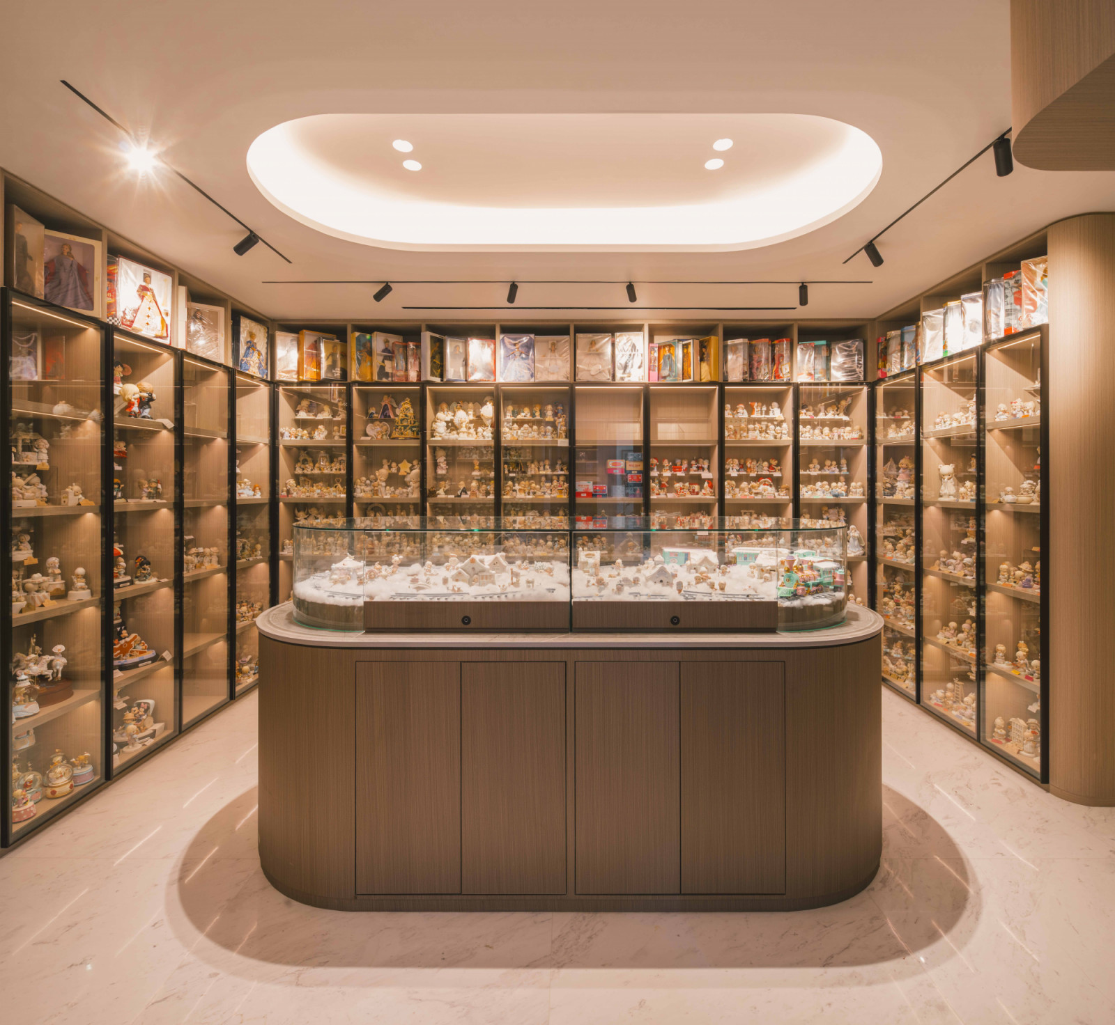 Full-height shelves showcase the wife’s treasured collection of dolls and figurines, with a central island serving as a stage for lively vignettes featuring these collectible pieces