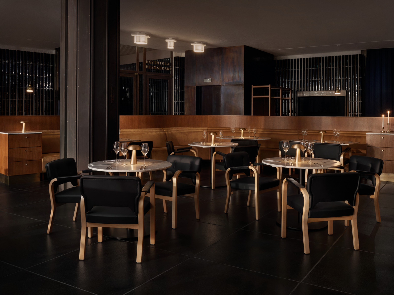 The main dining room at Finlandia Bistro, designed by Fyra, with original Aalto-designed birch and black leather armchairs, marble-topped tables and the building's original ribbed glass ceiling fixtures retained throughout