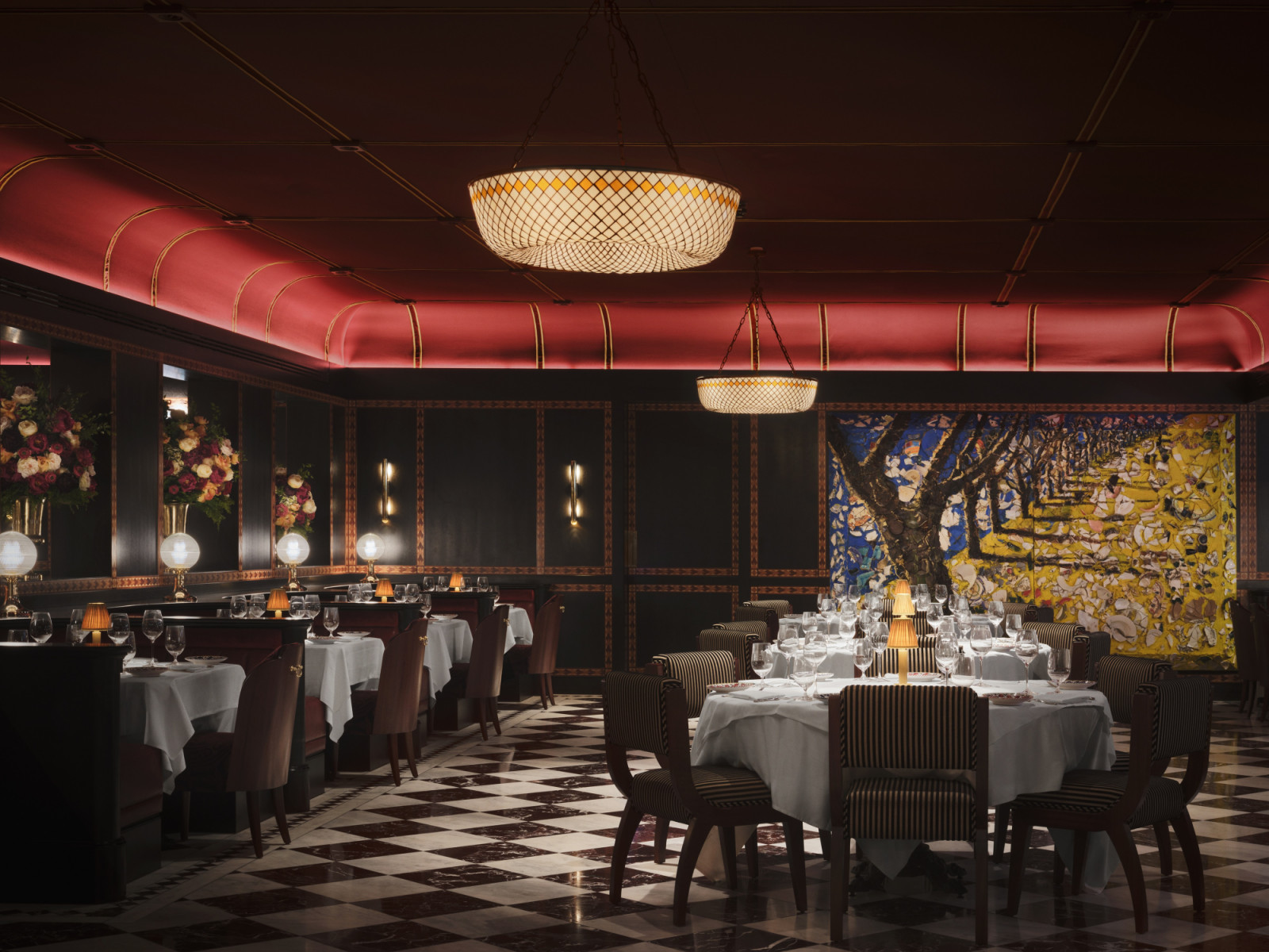 The main dining room at Carbone London with a crimson barrel-vaulted ceiling edged in brass, a large-scale painting on the end wall, black lacquered panelling and a chequered marble floor