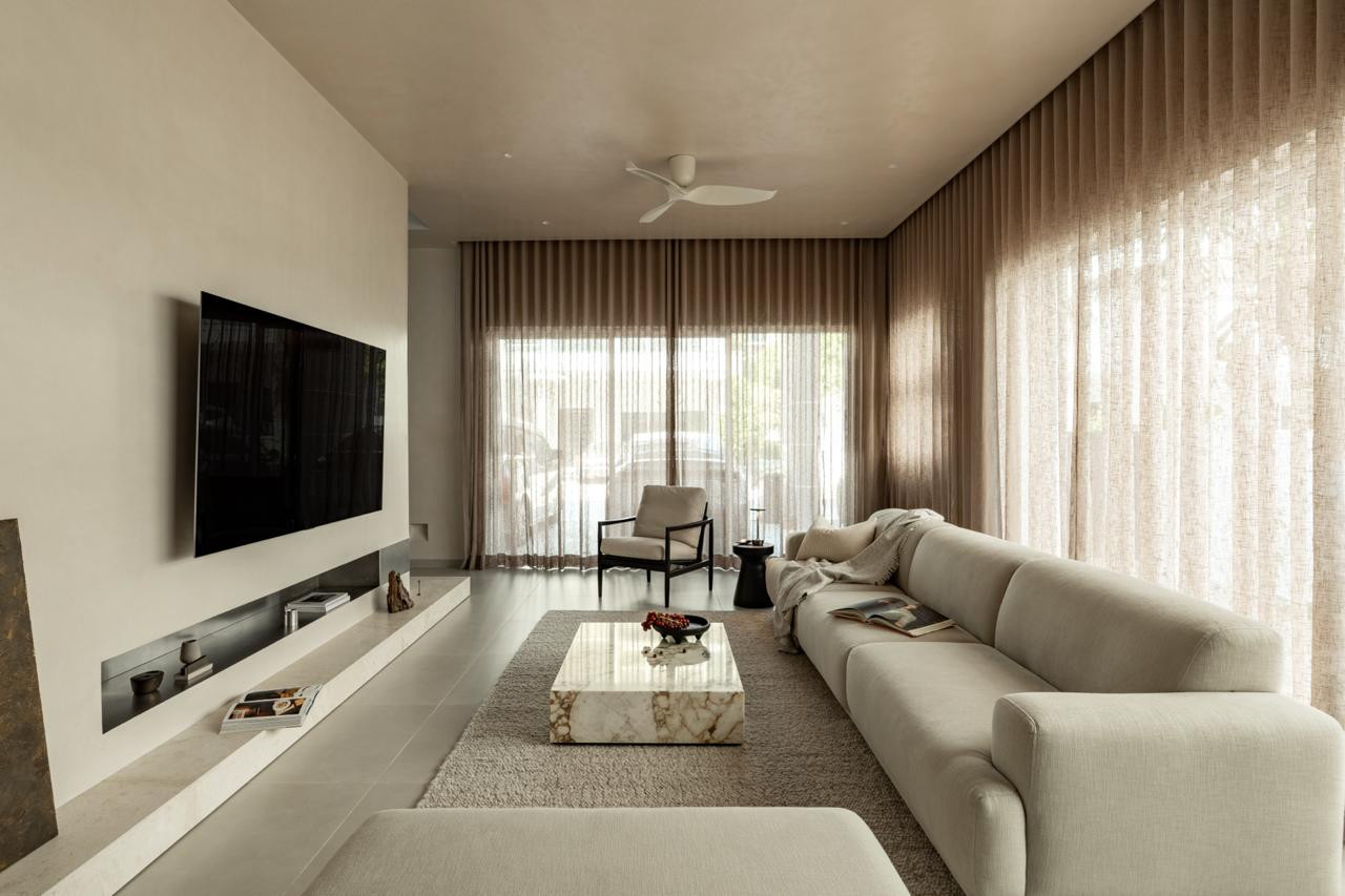 The living room, furnished with The Perabot’s SF01 Calm Sofa and a marble coffee table, faces floor-to-ceiling linen curtains that filter afternoon light from the garden