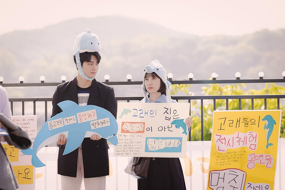 Extraordinary Attorney Woo featuring a scene wearing dophin hats and carrying dolphin placards (Photo: IMDB)
