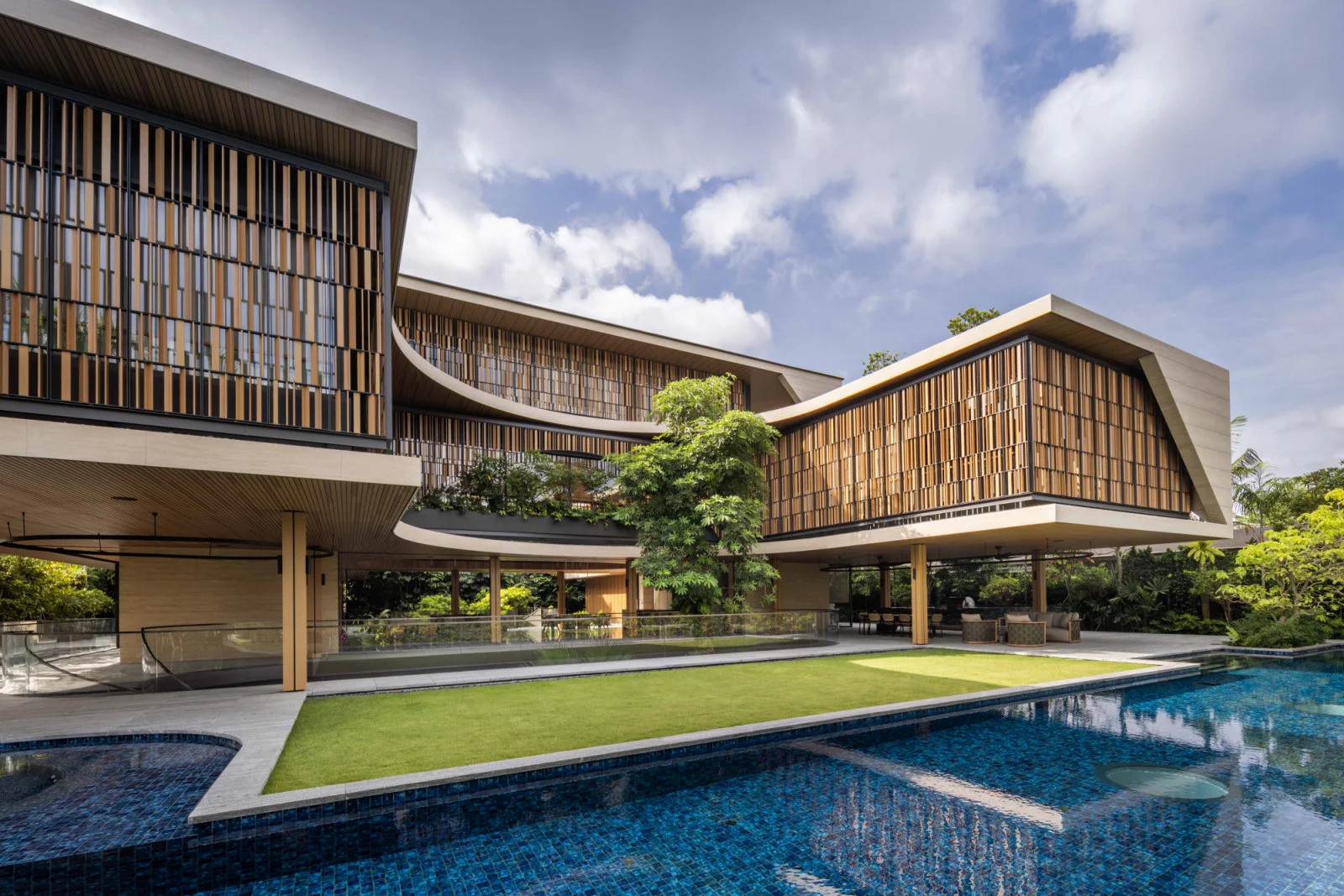 This view from the garden highlights how the Good Class Bungalow’s cooling pool channels breezes into the porous ground floor, tempering the tropical heat