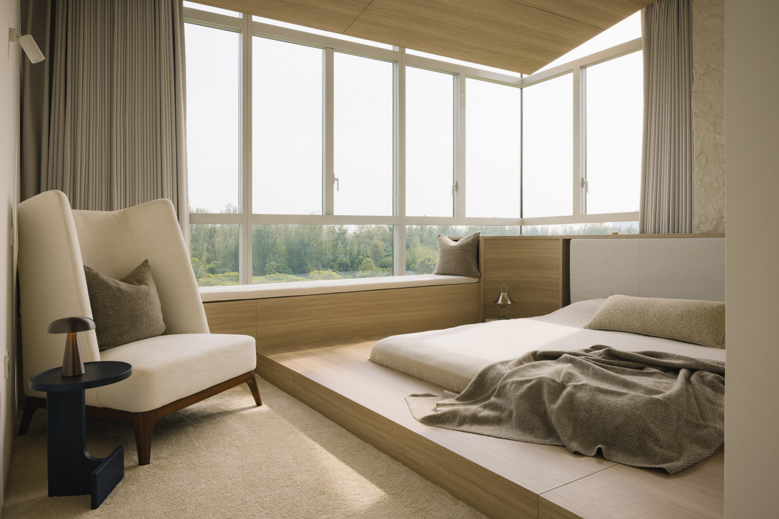 This bedroom offers an abundance of lounging options with its low-slung bed, armchair and bay window seat