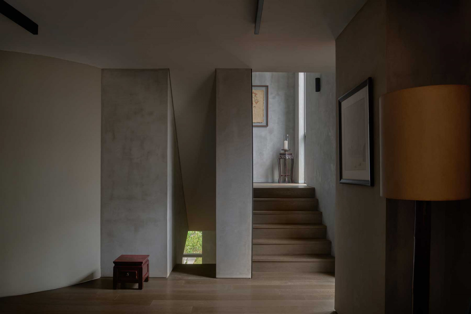 Natural light filters through a narrow opening beside the stairs, softly illuminating the 3D-printed walls and articulating the quiet spatial rhythm of the upper levels