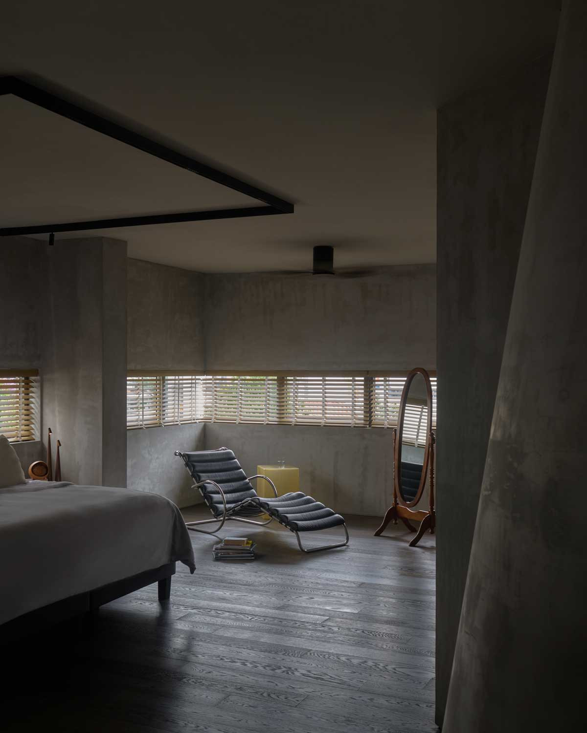 In the master bedroom, a corner window wraps the space with daylight while muted materials and curved 3D-printed surfaces maintain the house’s quiet spatial language
