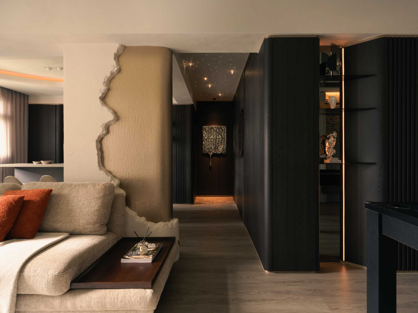 A striking feature wall—half raw plaster, half gilded—injects sculptural flair and subtle contrast into the soft, tonal interior