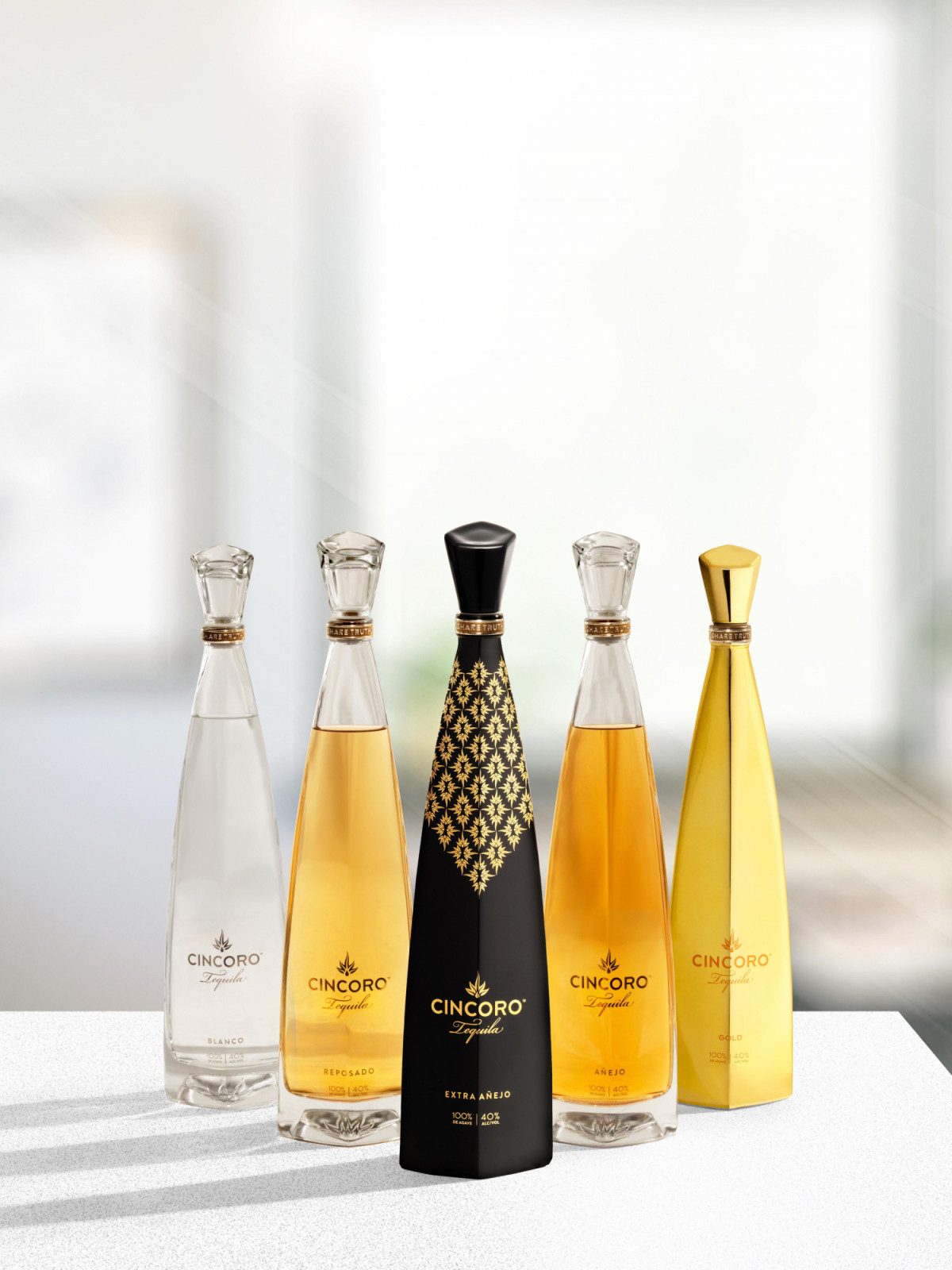 A premium lineup of Cincoro Tequila variants including Blanco, Reposado, Añejo, and Extra Añejo bottles in a luxury setting