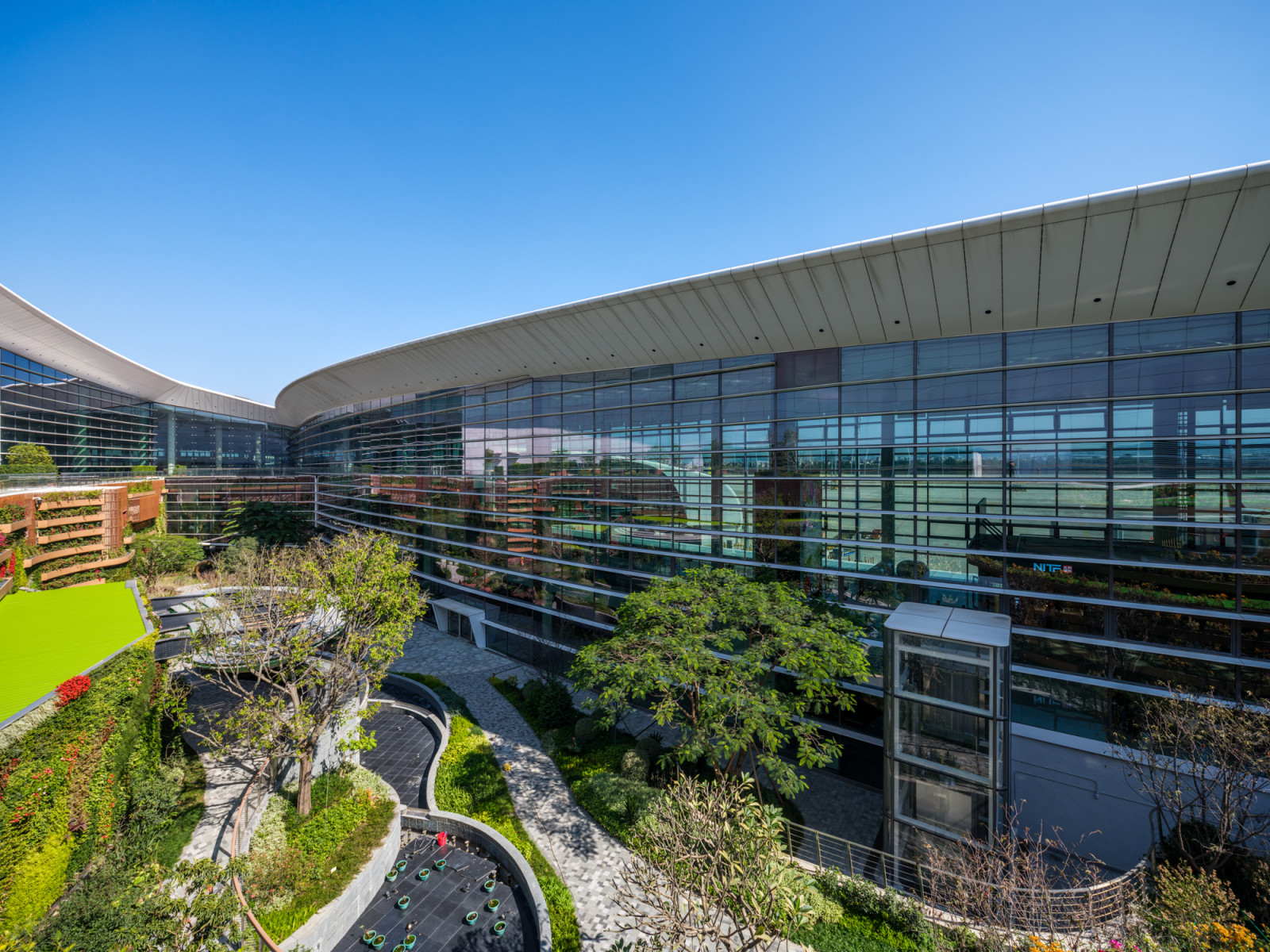 A terraced rooftop garden at Guangzhou Baiyun International Airport’s Terminal 3, with curved glazed facades and planted terraces overlooking the runway (Photo: 李开建/Li Kaijian)