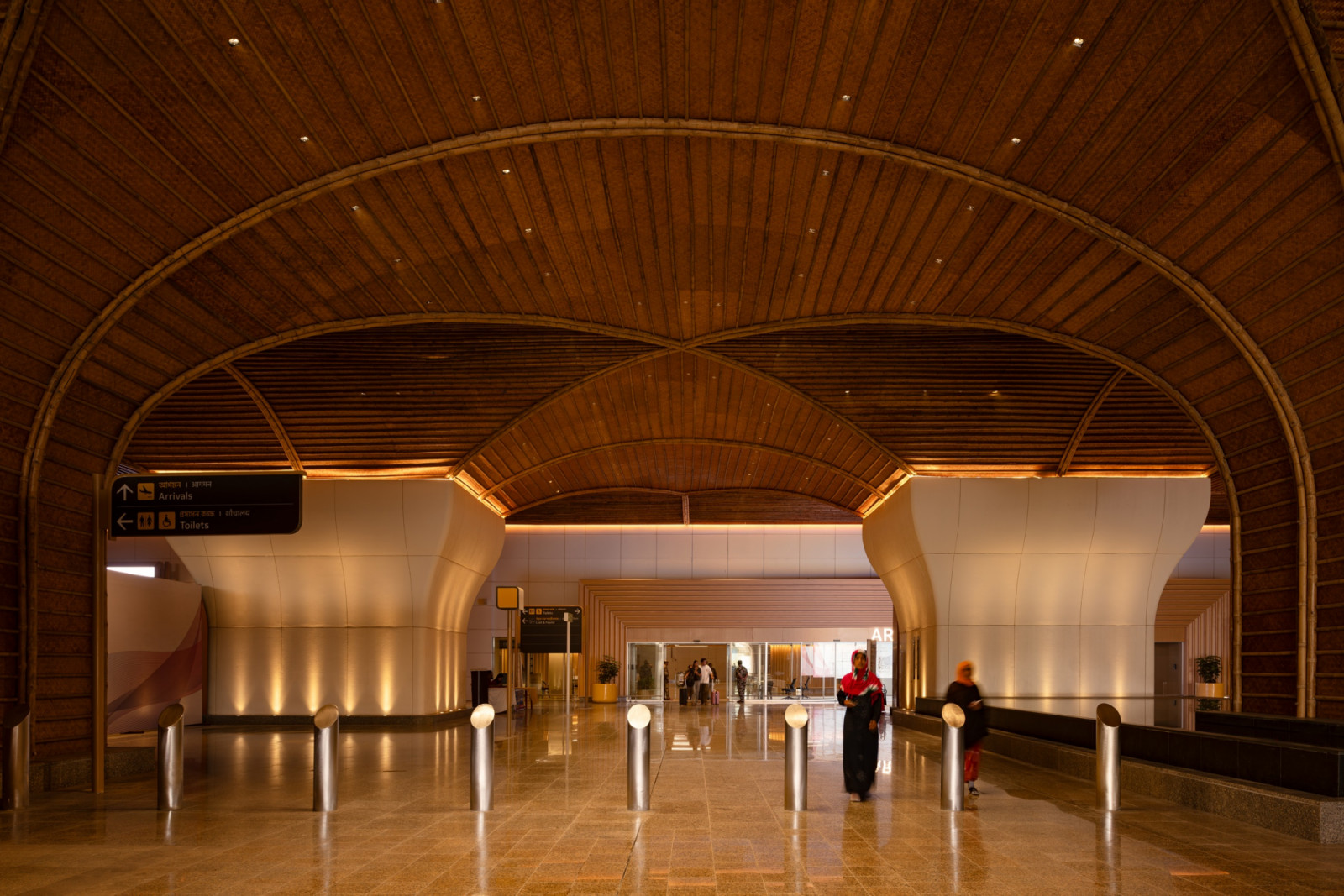 The arrivals hall is crowned by a sweeping bamboo barrel vault, its woven lattice ribs evoking the form of a traditional Assamese boat or basket structure