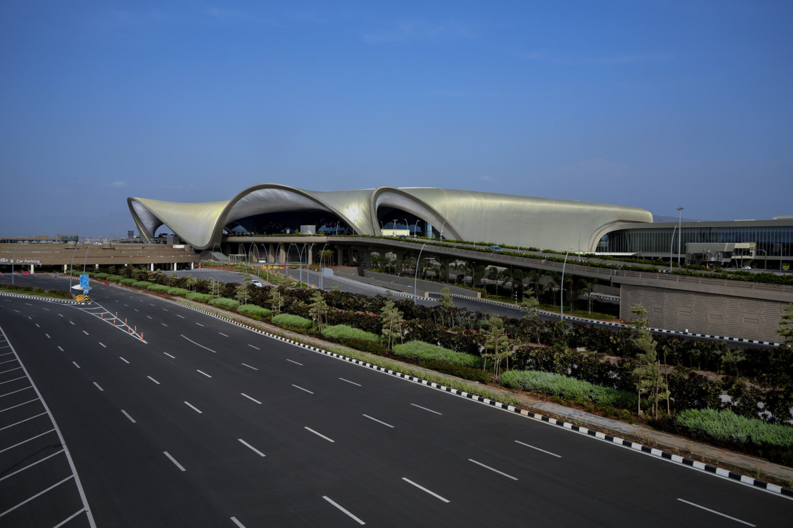 Designed by Zaha Hadid Architects, the terminal’s roof extends in sweeping overhangs, its golden petal forms appearing to open towards the morning light