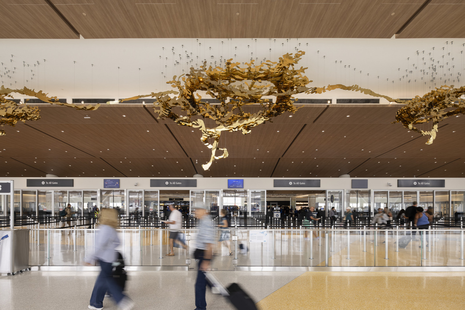 A sweeping gold sculptural form drifts across the wood-clad ceiling of the departures hall, part of the terminal’s curated digital and physical art programme (Photo: Ema Peter)
