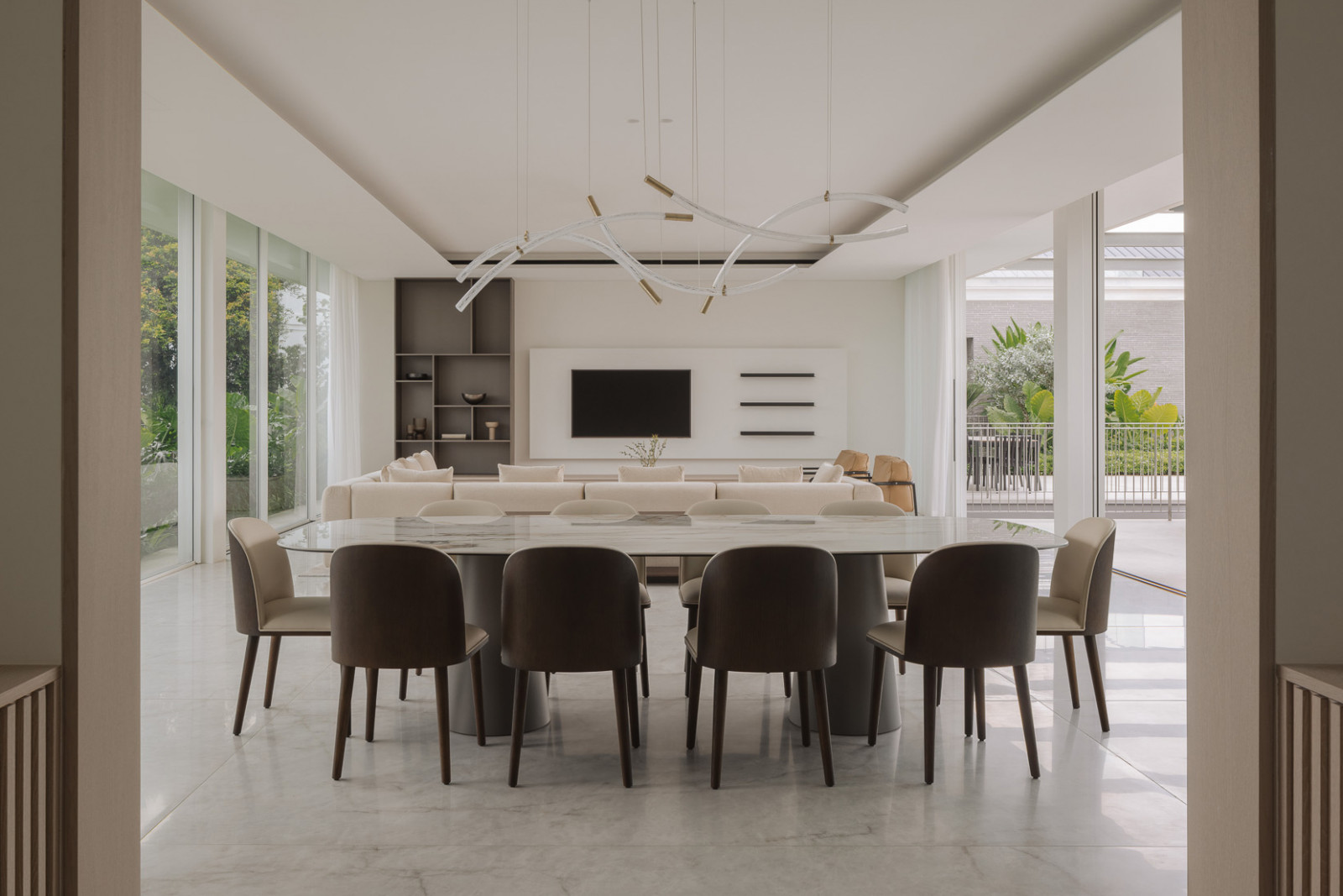 A 10-seater dining table gracefully commands the space beneath a Bomma Flare Suspension Lamp