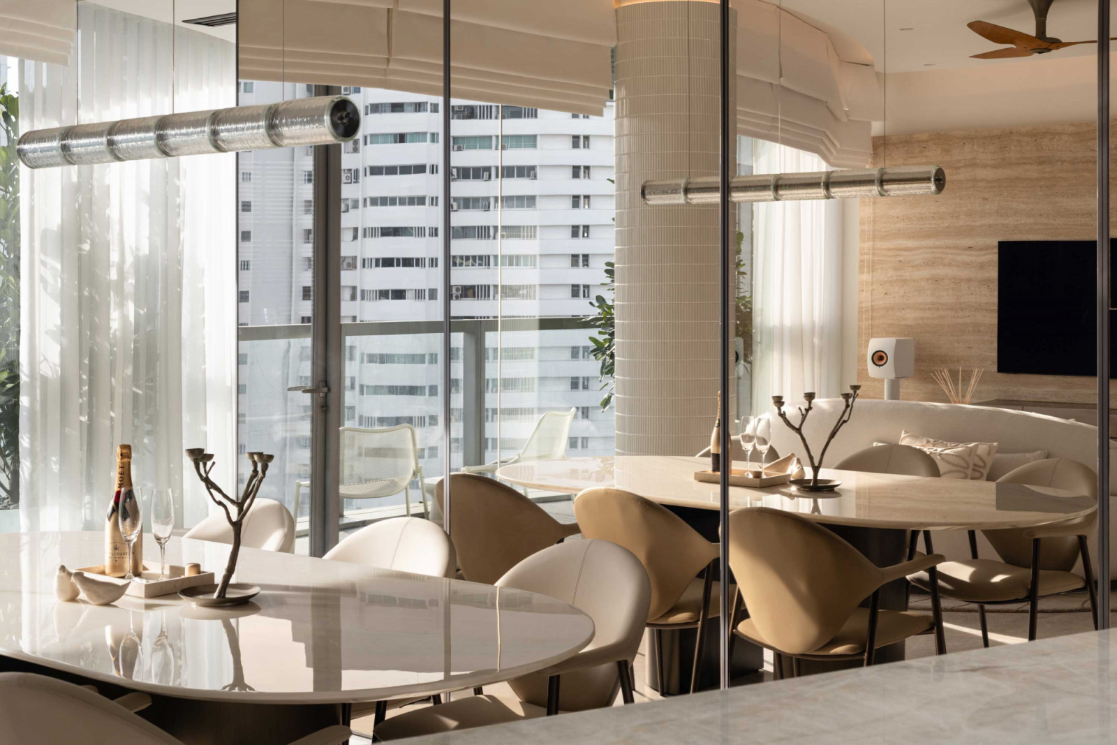 In the dining area, a curved table and upholstered chairs echo the home’s soft, sculpted lines