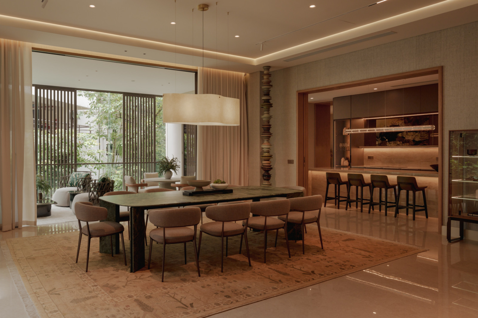 The dining area at Eden Taman Duta’s show unit, with a green marble table and views through to the show kitchen and the surrounding greenery beyond