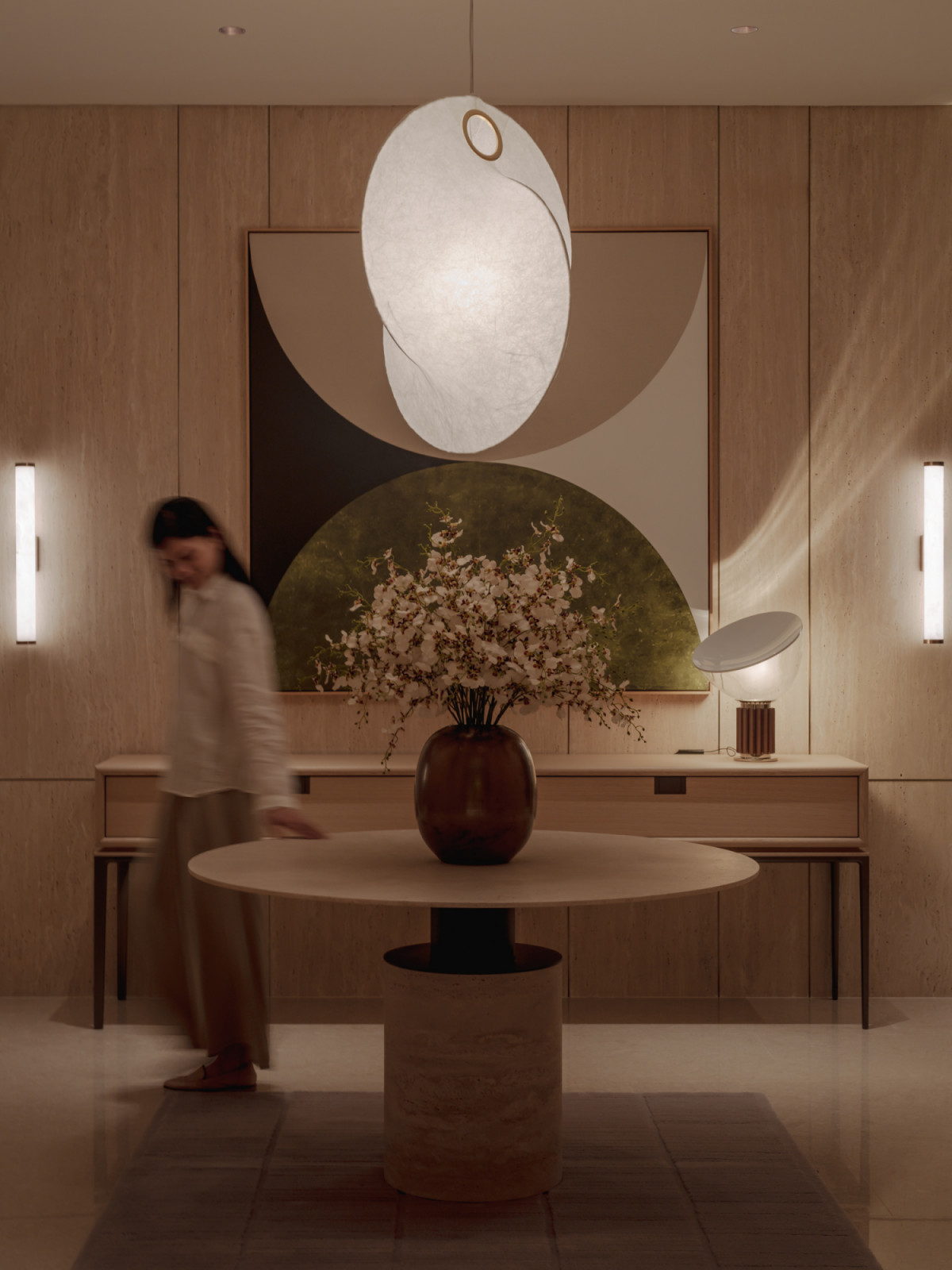 The entry gallery at Eden Taman Duta’s show unit, where travertine wall panelling and a sculptural pendant light frame the arrival sequence