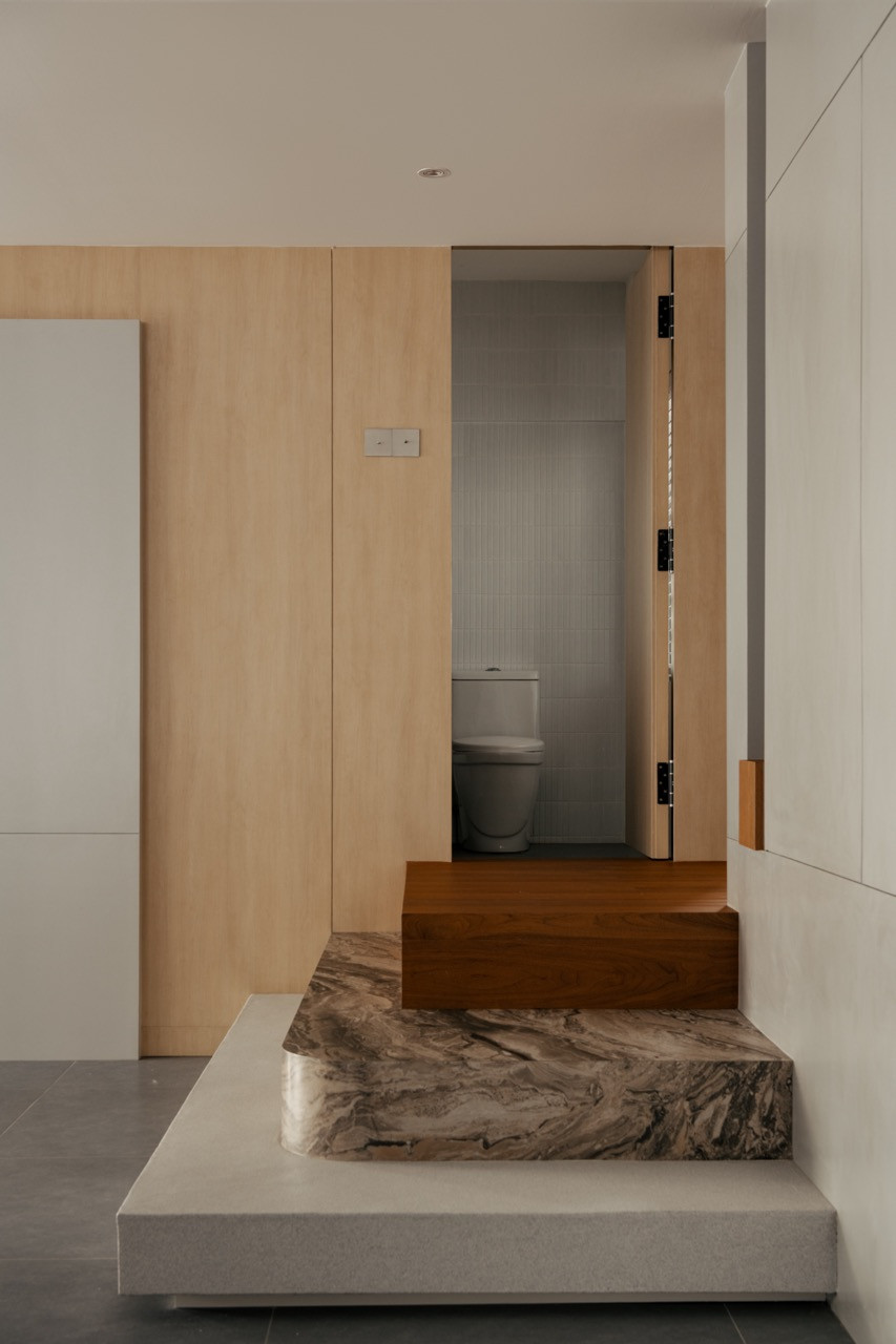 The three-step staircase at the base of the upper-floor entry, with the guest bathroom door visible behind, finished in oak-toned wall panelling