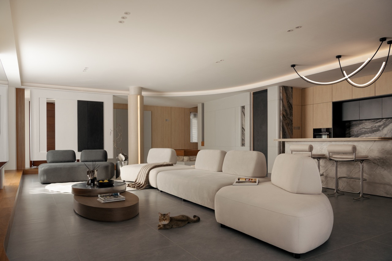 Full ground-floor view from the living area through to the kitchen, showing the curved ceiling, modular sofa grouping, round coffee table, Bianco Carrara marble island, and looped pendant light