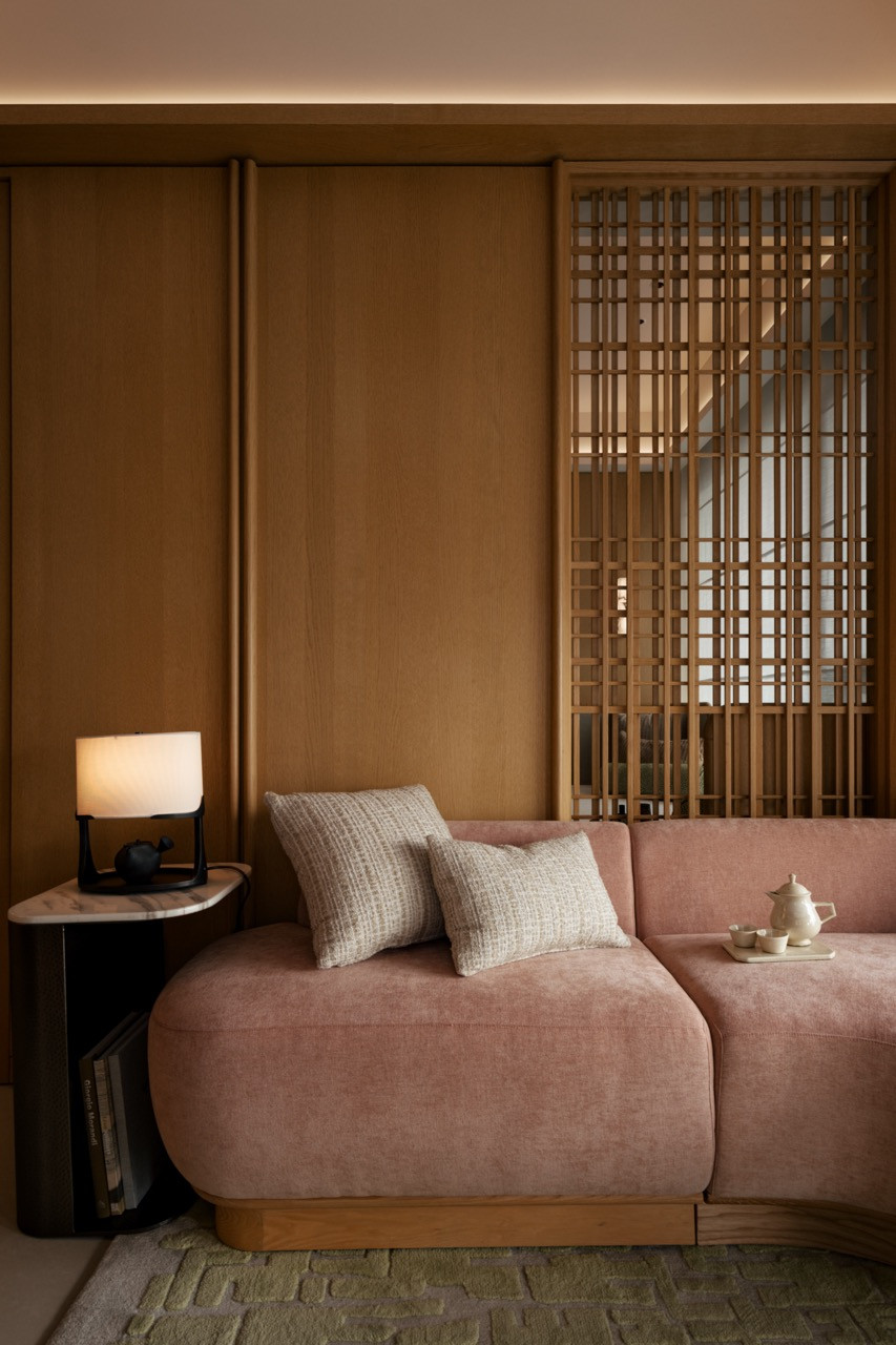 The Type S living area anchored by a deep pink sofa against warm timber paneling