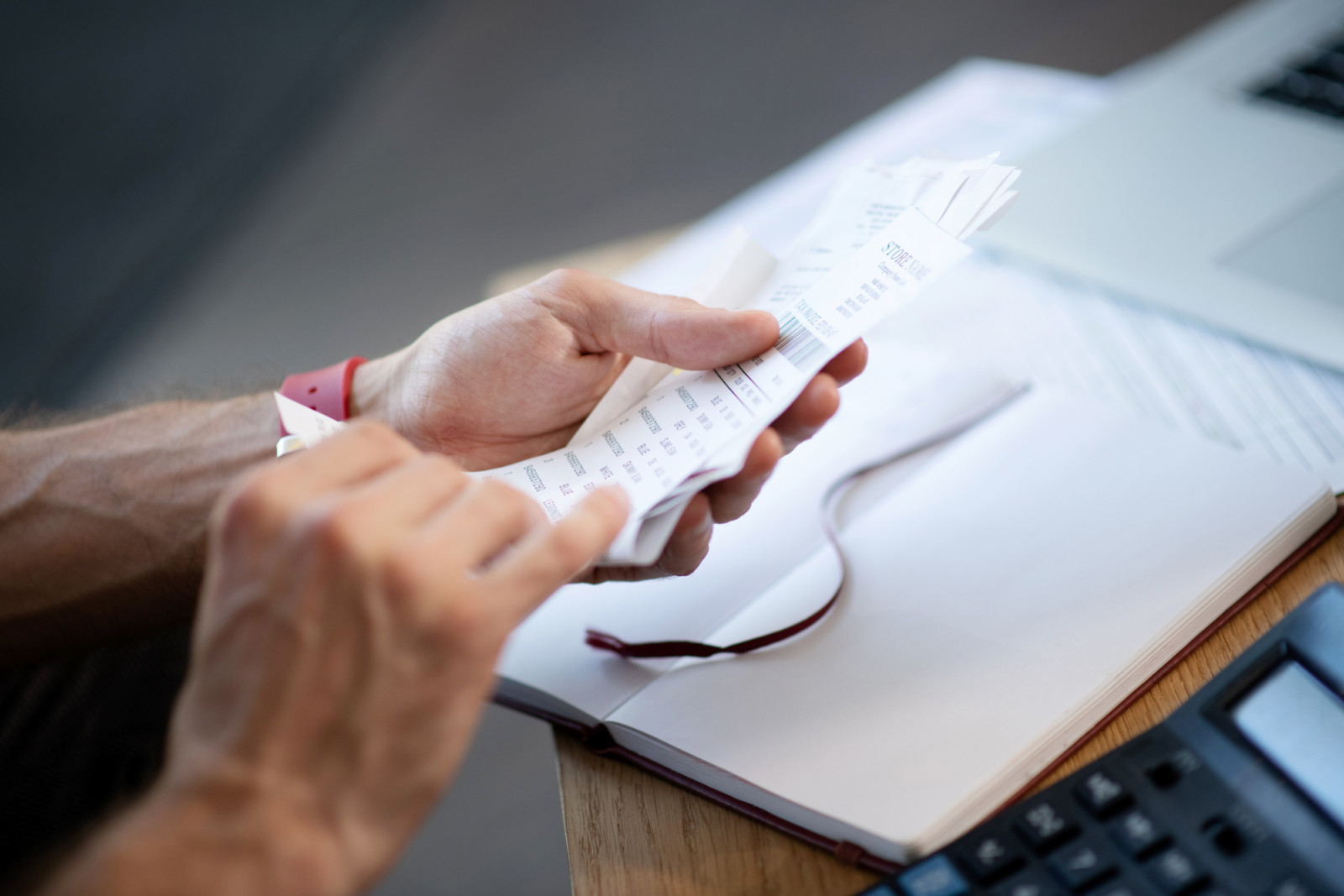 Businessman holding bills. Close up of busy young businessman holding bills while studying expenses