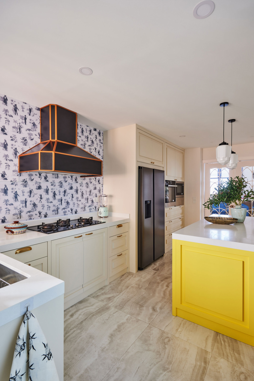 Even the kitchen is brightened up with patterned wallpaper and a cheery yellow island