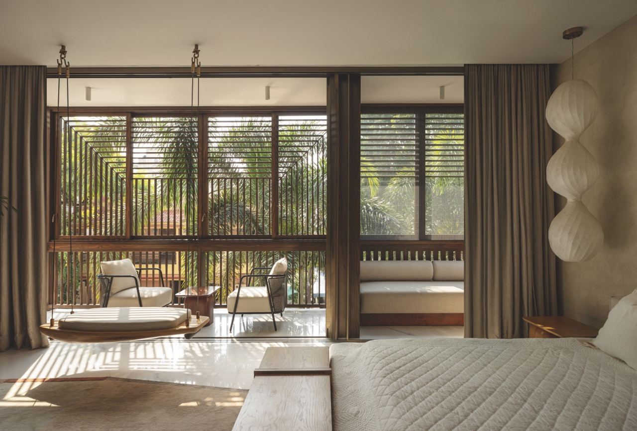 A bedroom in neutral tones that opens out to a snug balcony shaded by lattice screens