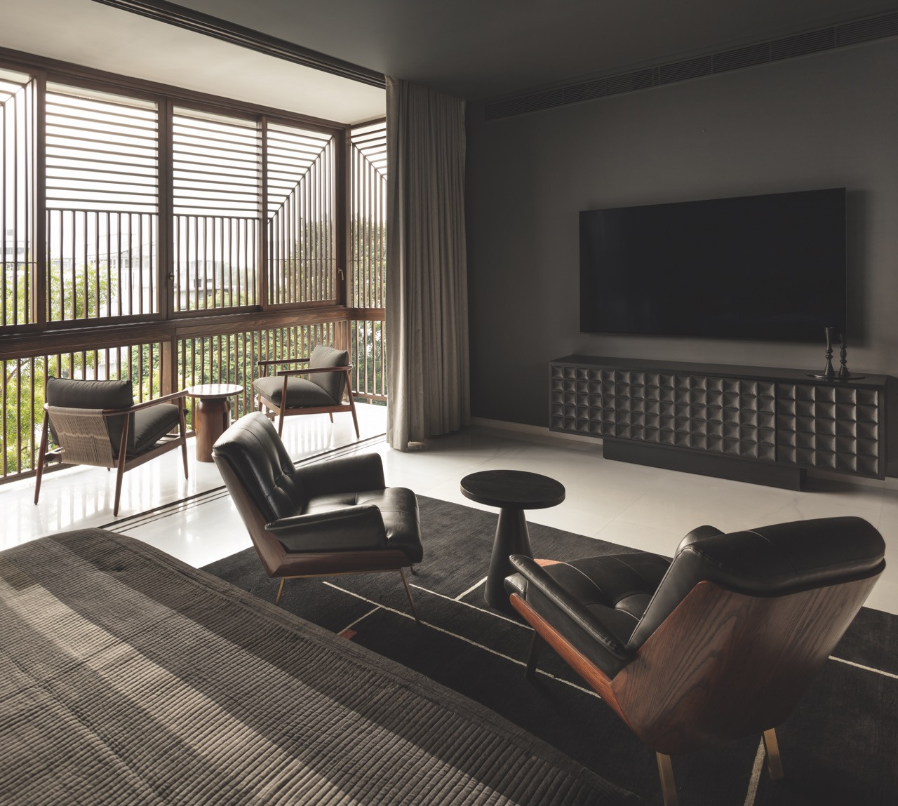 The grandson’s suite, finished in dark tones with leather chairs and lattice-filtered light
