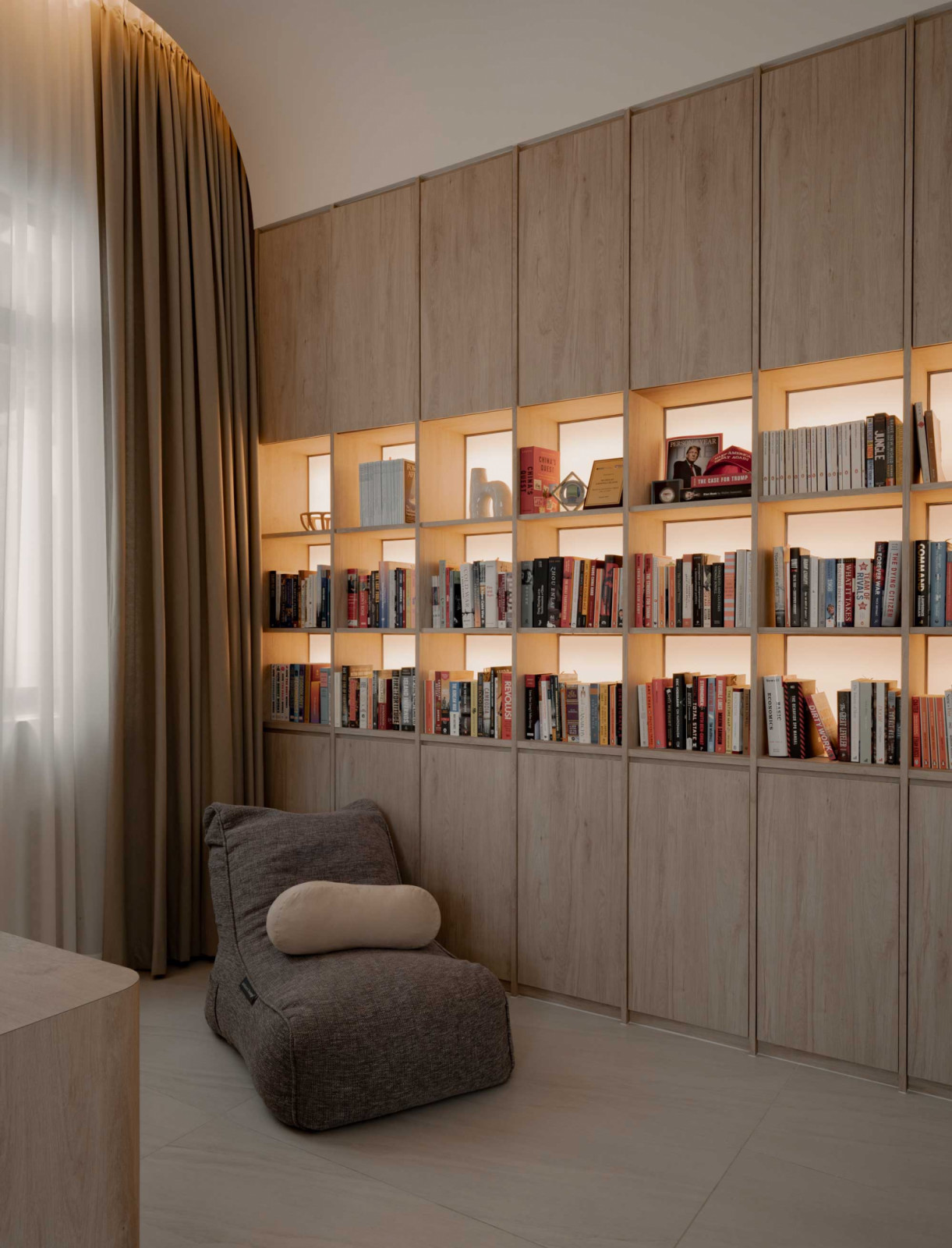 A built-in bookshelf with integrated lighting forms a quiet reading corner