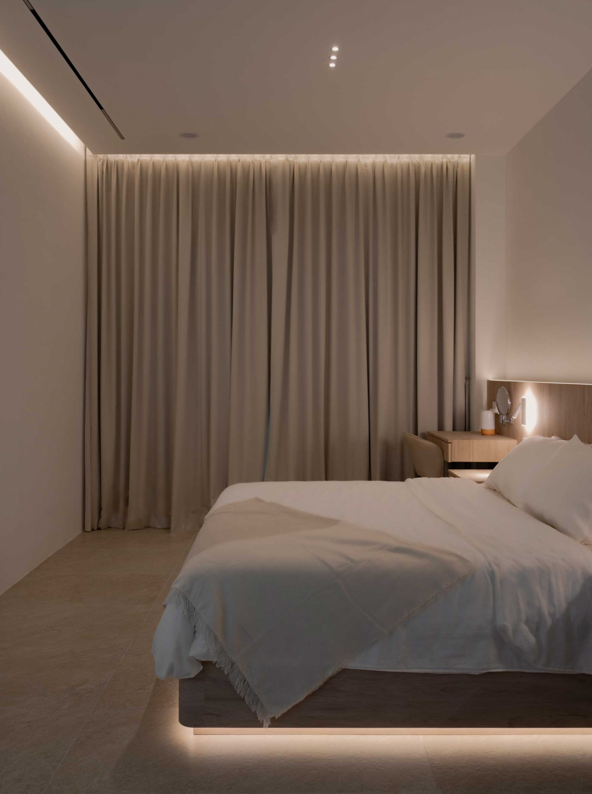 This bedroom is minimalist and serene, with soft lighting and full-height curtains