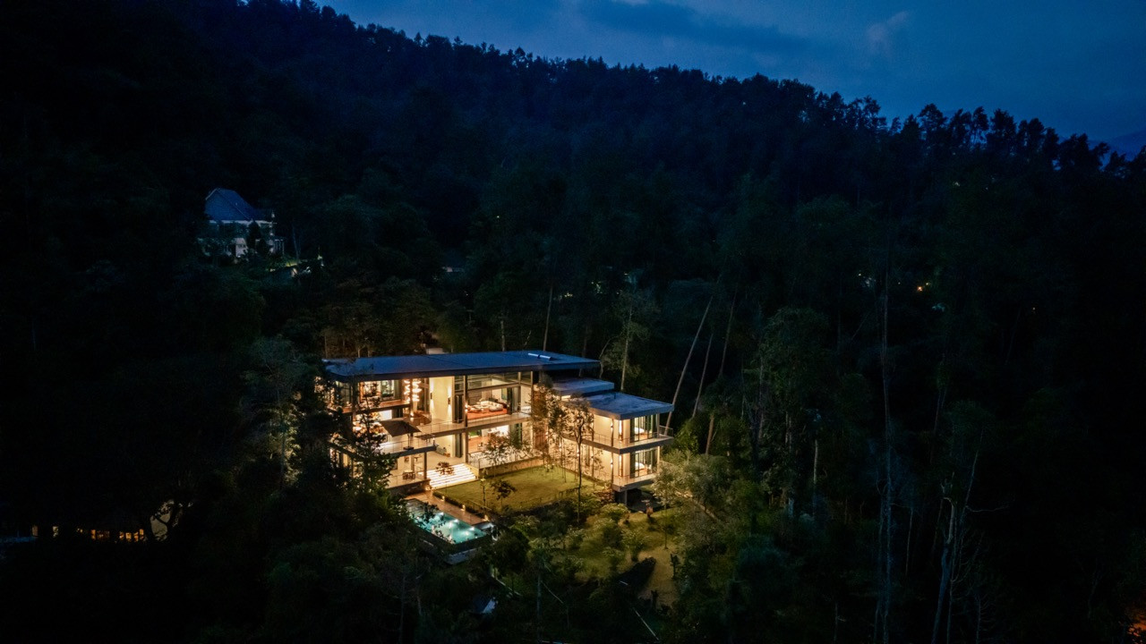 An aerial view of Liù Lín Residence at night, set within the wooded foothills of Janda Baik