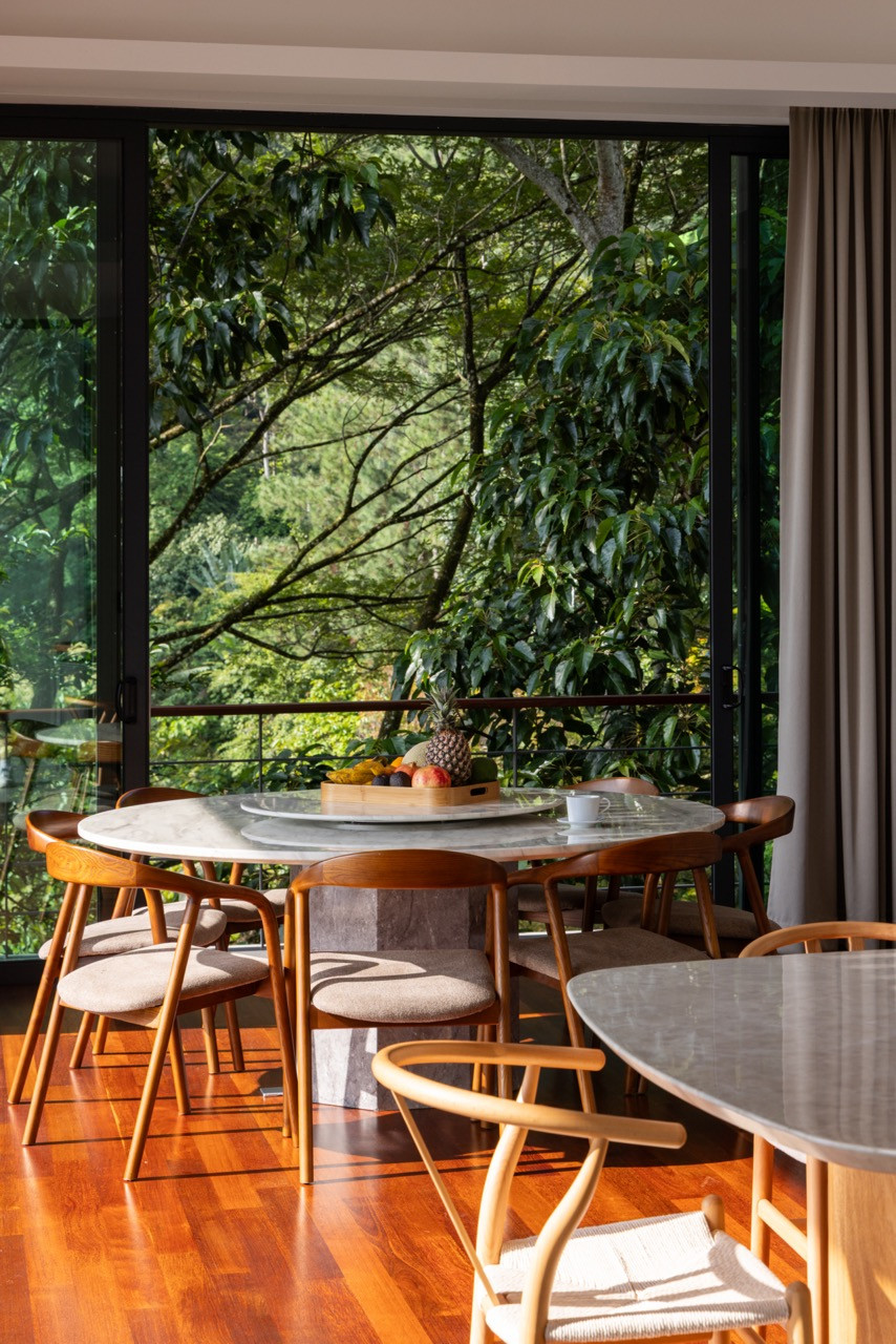 The dining room, with a round marble-topped table and timber chairs set against full-height glazing