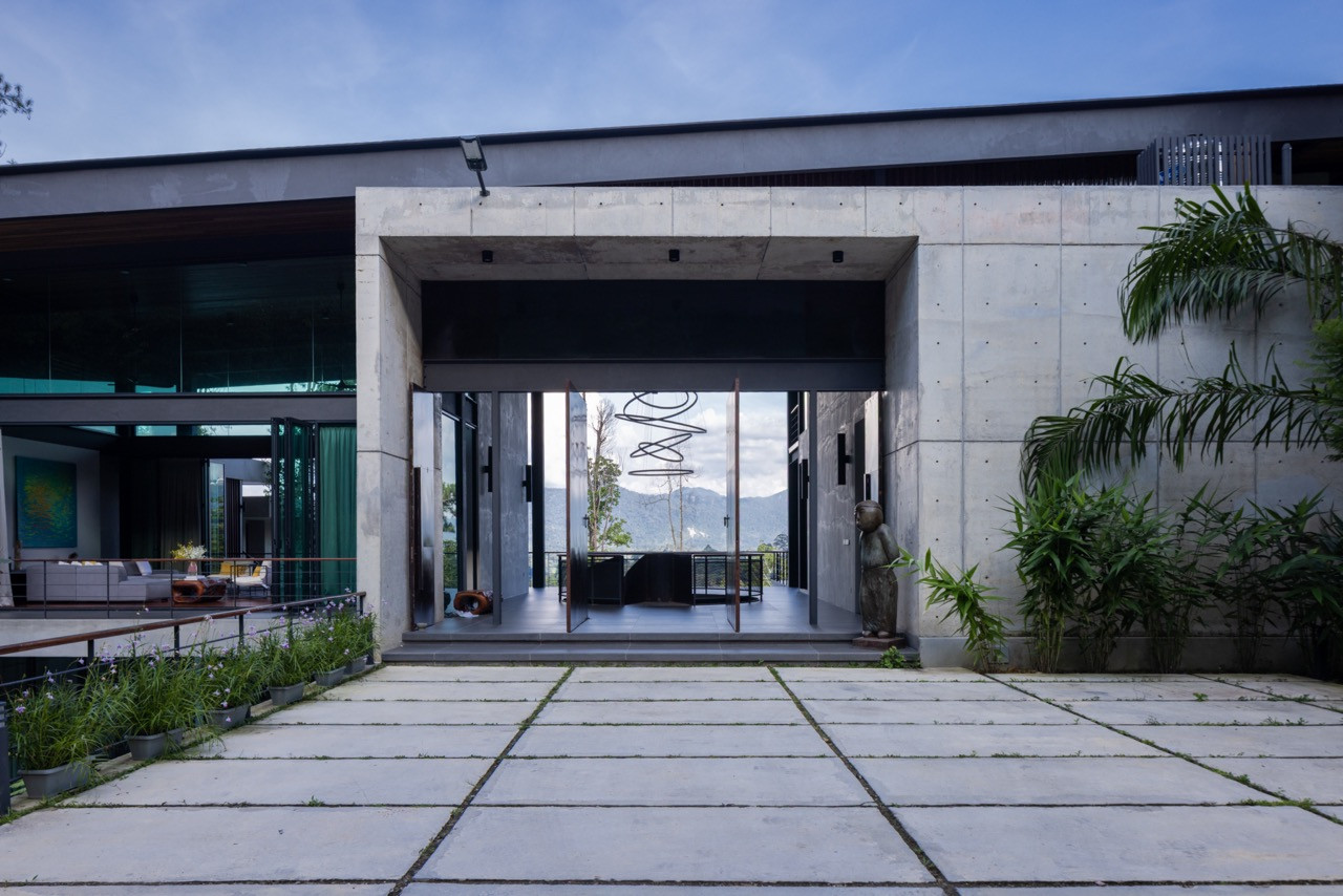 The entrance forecourt, with stone paving leading to the lobby; the front facade viewed from the garden courtyard, with the upper-level living and dining areas open behind folding glass walls