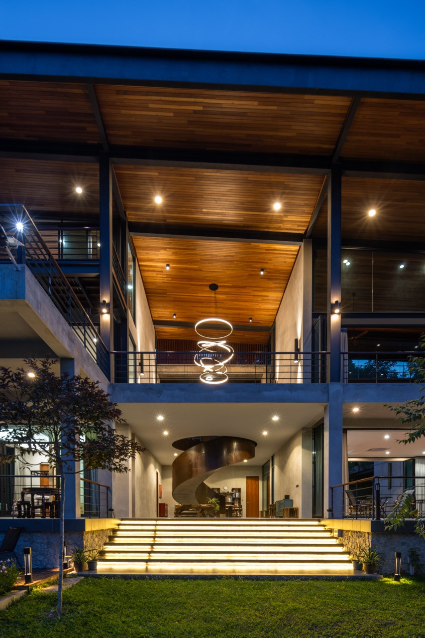 The entrance lobby from the garden, with three pivoted steel doors open and the curved staircase visible within