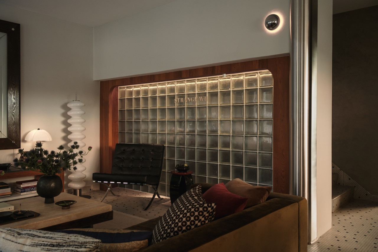 The main living area, anchored by a backlit glass block wall etched with the studio’s name