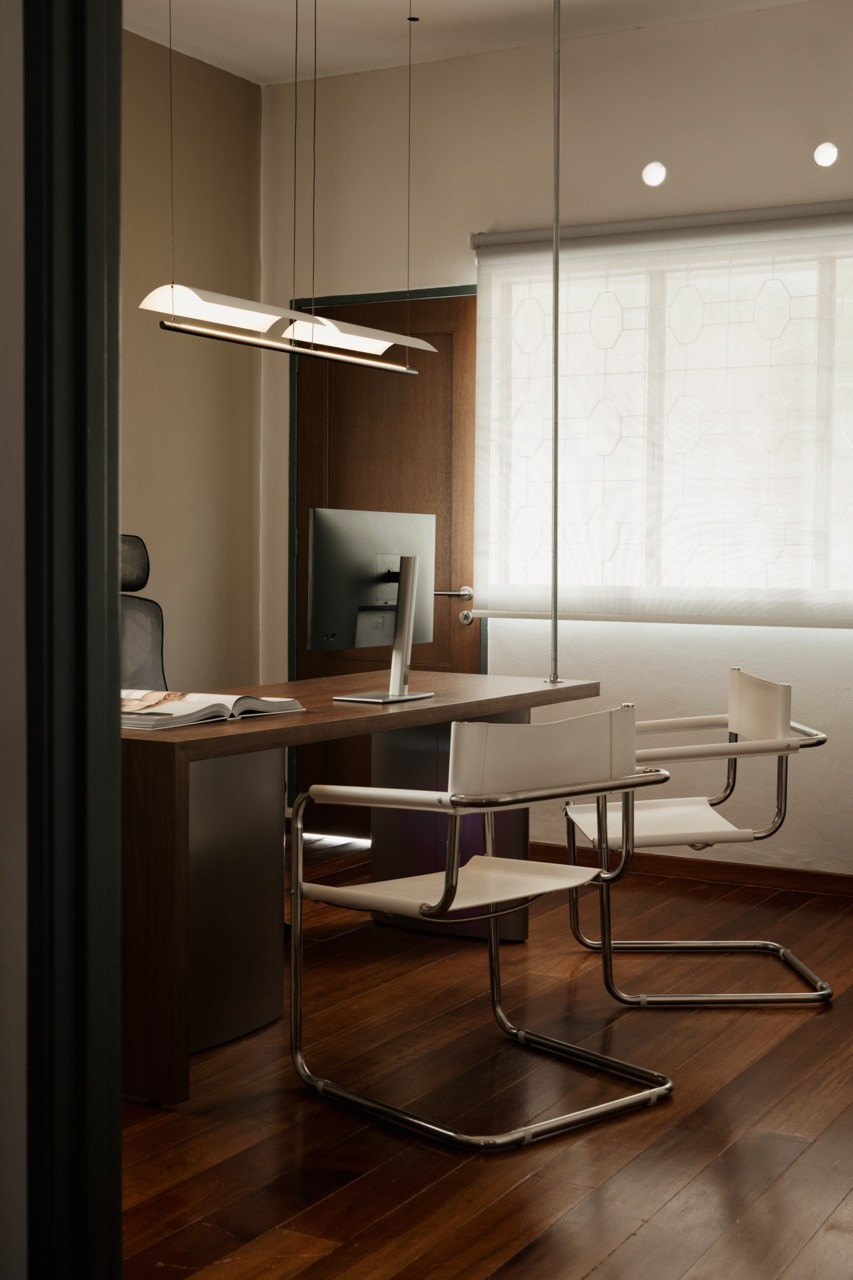 The meeting room, seen through the doorway with a timber desk and chrome tubular cantilever chairs