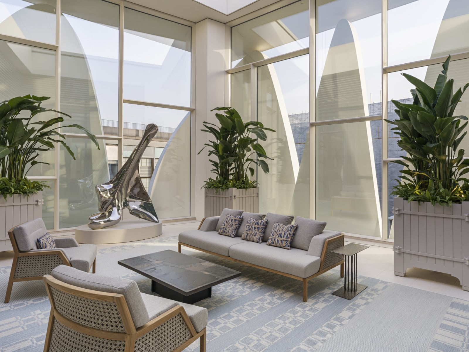 The rooftop lounge area is furnished with rattan and teak seating, its planting echoed by the petal forms visible through the glazing (Photo: Kristen Pelou)