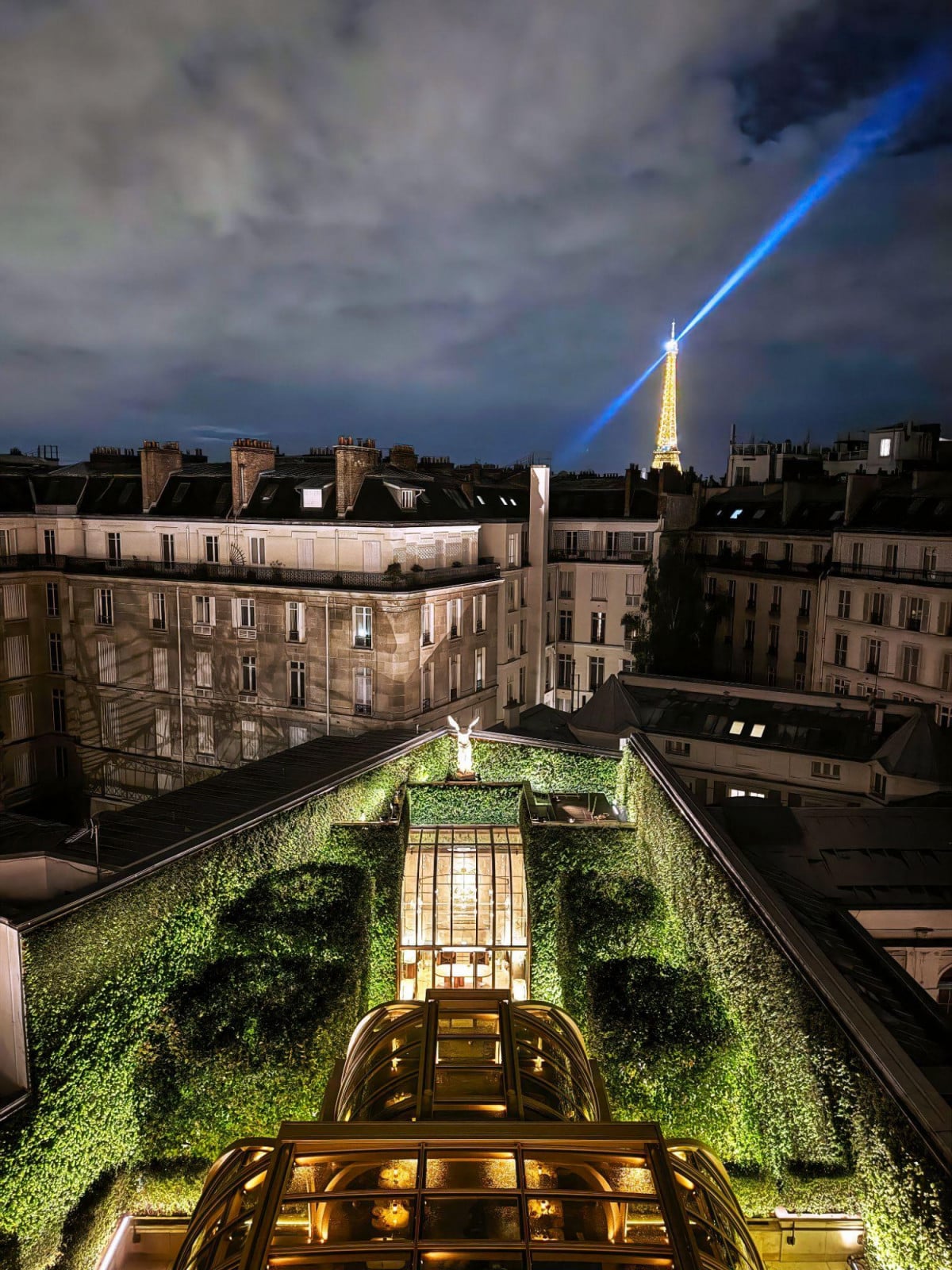 Viewed from above, the building’s planted roof terrace sits beneath a glass dome, with the Eiffel Tower visible across the Paris rooftops (Photo: Kristen Pelou)