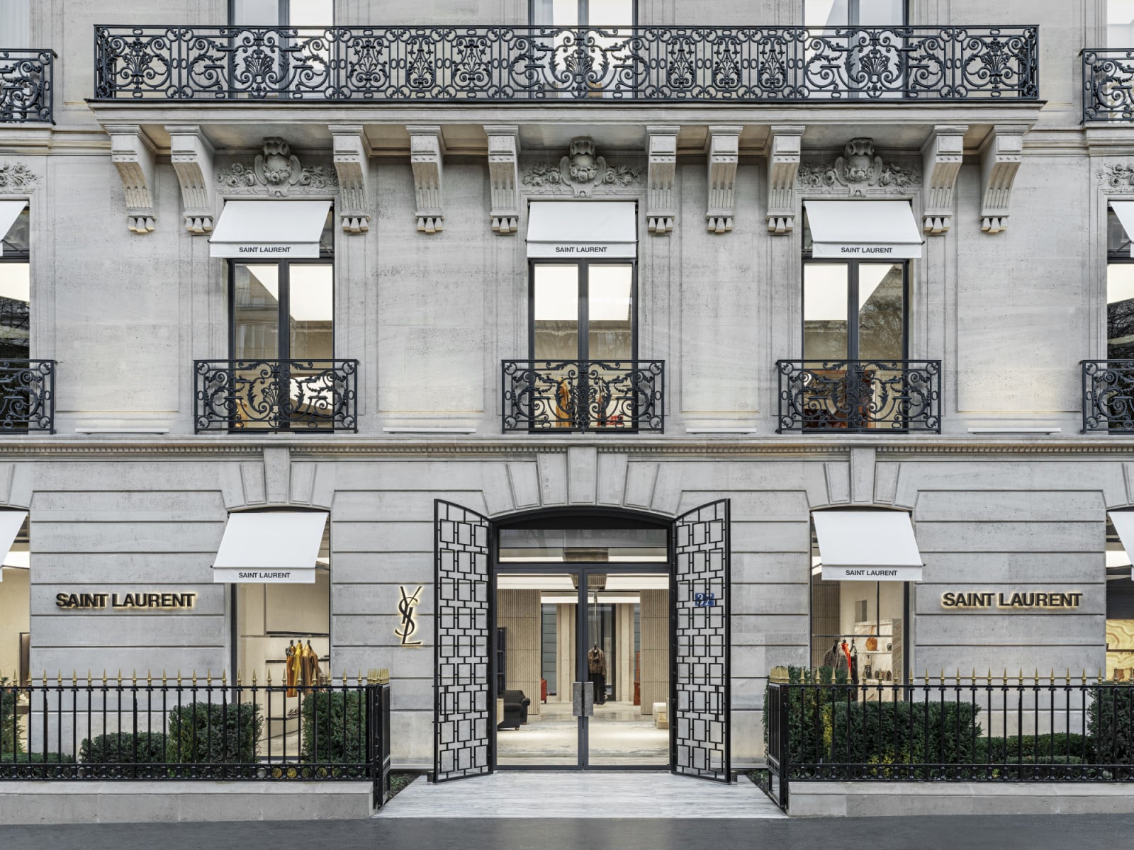 The Montaigne façade retains its original stone and wrought-iron balconies, with the Saint Laurent signage set discreetly beside the entrance (Photo: Adagp)