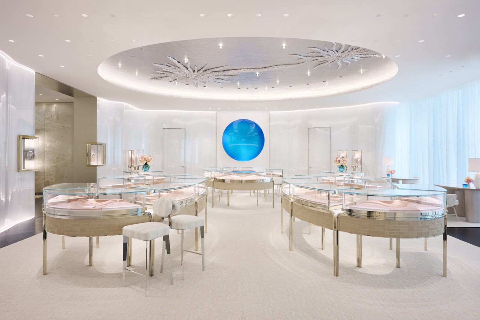 Beneath a circular ceiling detailed in silvered coral-like forms, curved display counters in woven bronze fan out across the salon
