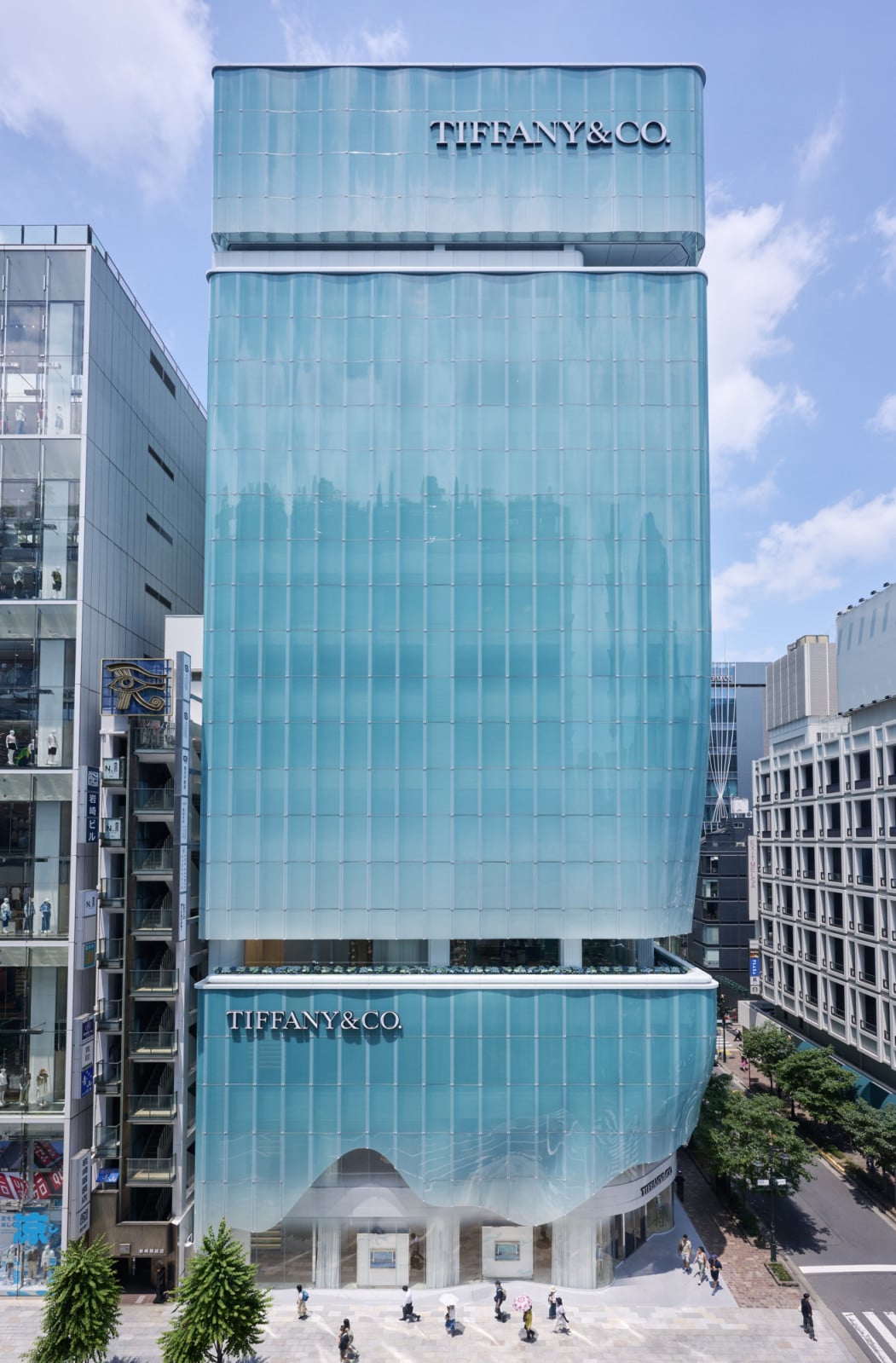 Viewed from above, the Ginza store’s glass panels stack into a tapered blue form rising above the surrounding streetscape
