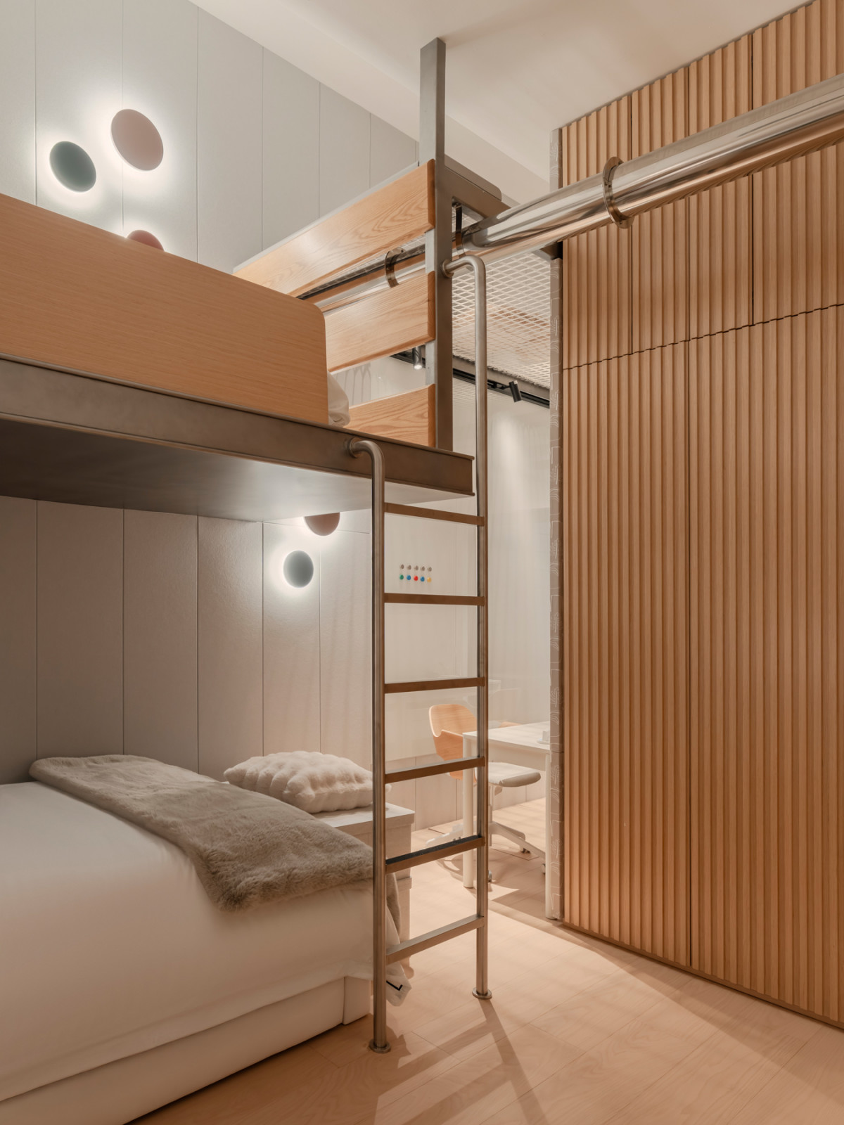 A detail of the children’s bunk bedroom, showing the metal ladder, the platform bed with its timber surround, and the grooved timber wardrobe panels