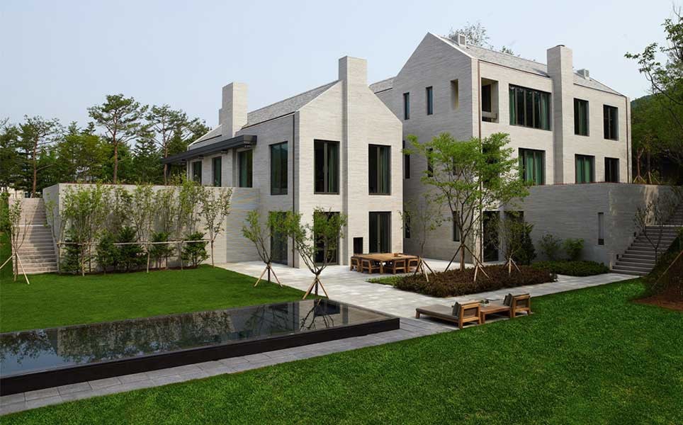 The rear elevation of the house is clad in long horizontal bricks of local granite, with a shallow reflecting pool running along the garden terrace (Photo: Studio Piet Boon)