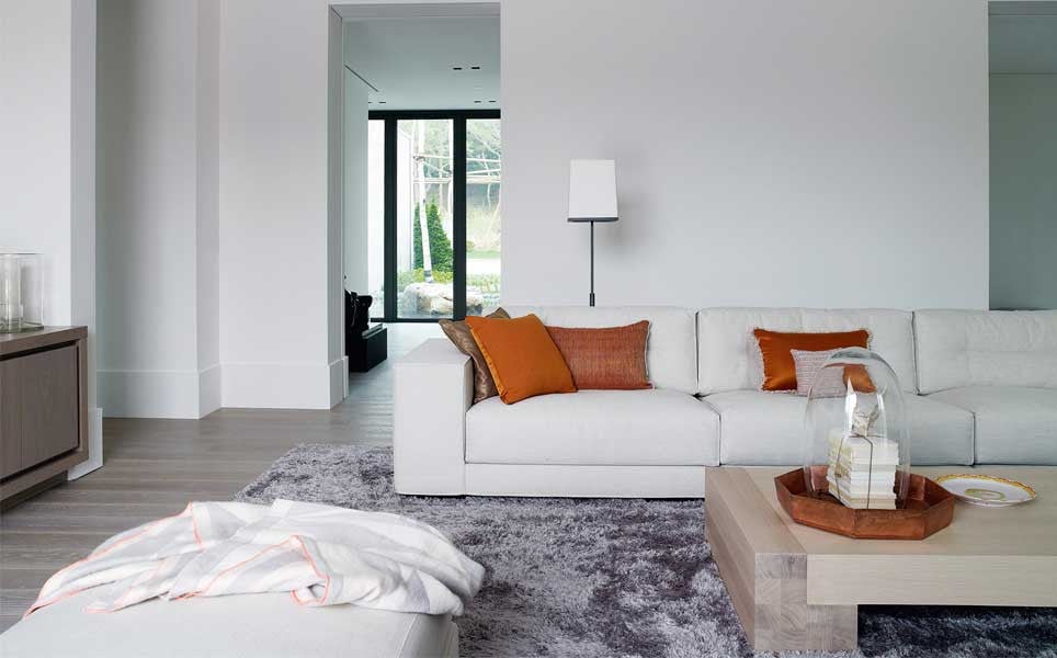 The living room, furnished in the studio’s signature palette of off-whites and warm neutrals, with floor-to-ceiling glazing looking onto the birch courtyard beyond (Photo: Studio Piet Boon)
