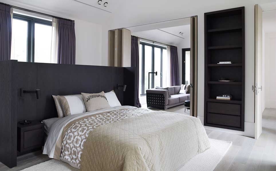One of two bedrooms, with dark-stained timber joinery and an open connection to a sitting area (Photo: Studio Piet Boon)