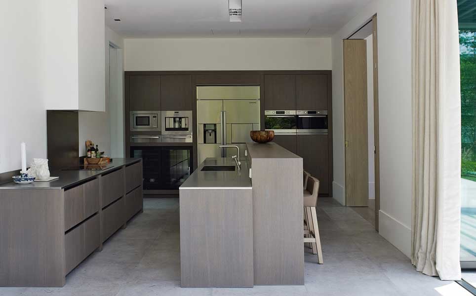 The kitchen is fitted with handleless cabinetry in a greyed oak finish and a central island in the same material (Photo: Studio Piet Boon)