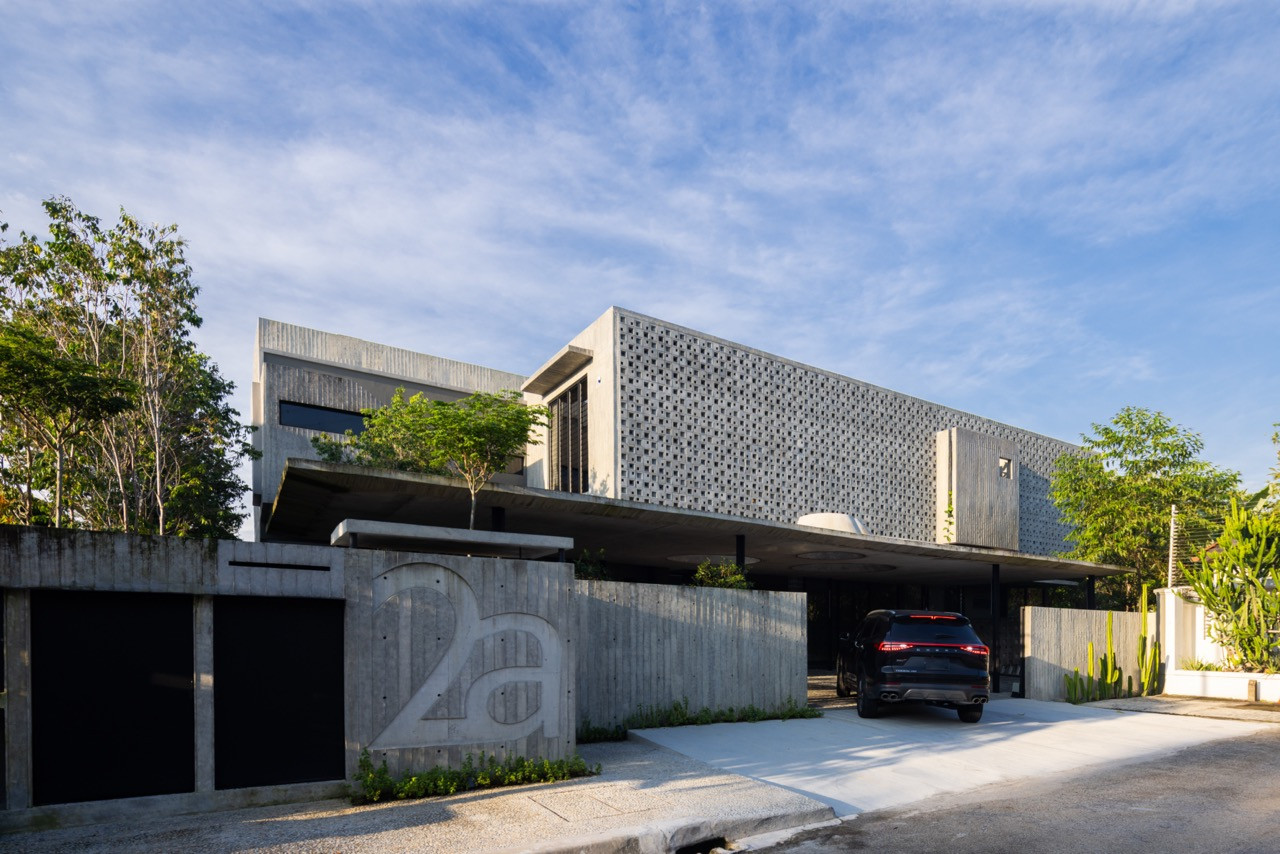 The street-facing facade is defined by the pixelated concrete vent filters spanning the full length of the bedroom band, which also function as sun shading and privacy screens for the rooms within